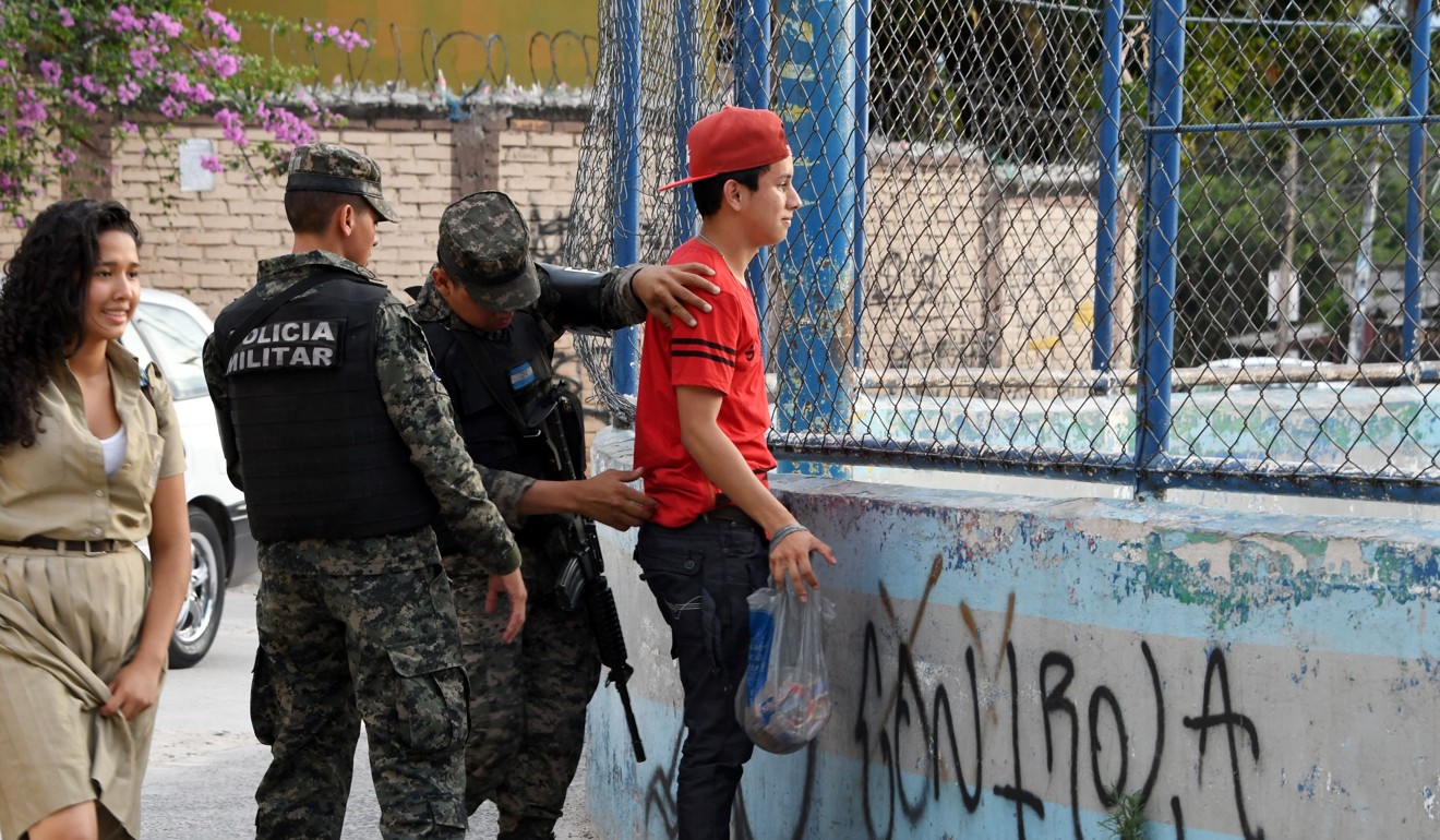 Military Police soldiers frisk a young man in the MS-13-controlled El Bosque neighbourhood in Tegucigalpa. The territorial fight between rival gangs has forced hundreds of people to flee. Photo: AFP