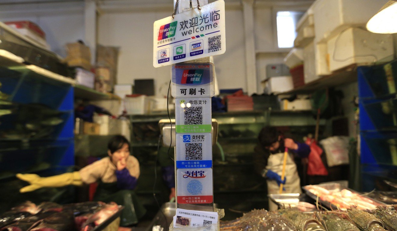 Placards on a seafood stall show various non-cash ways to pay, including QR codes of WeChat and AliPay, at a market in Beijing, in 2016. Photo: EPA