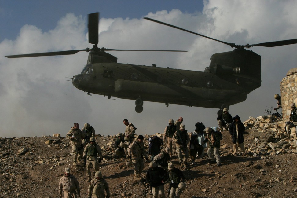 A Chinook helicopter hovers over US troops in the village of Jegdelic, about 56 miles southwest of Kabul, Afghanistan, December 24, 2004. Photo: REUTERS/Ahmad Masood
