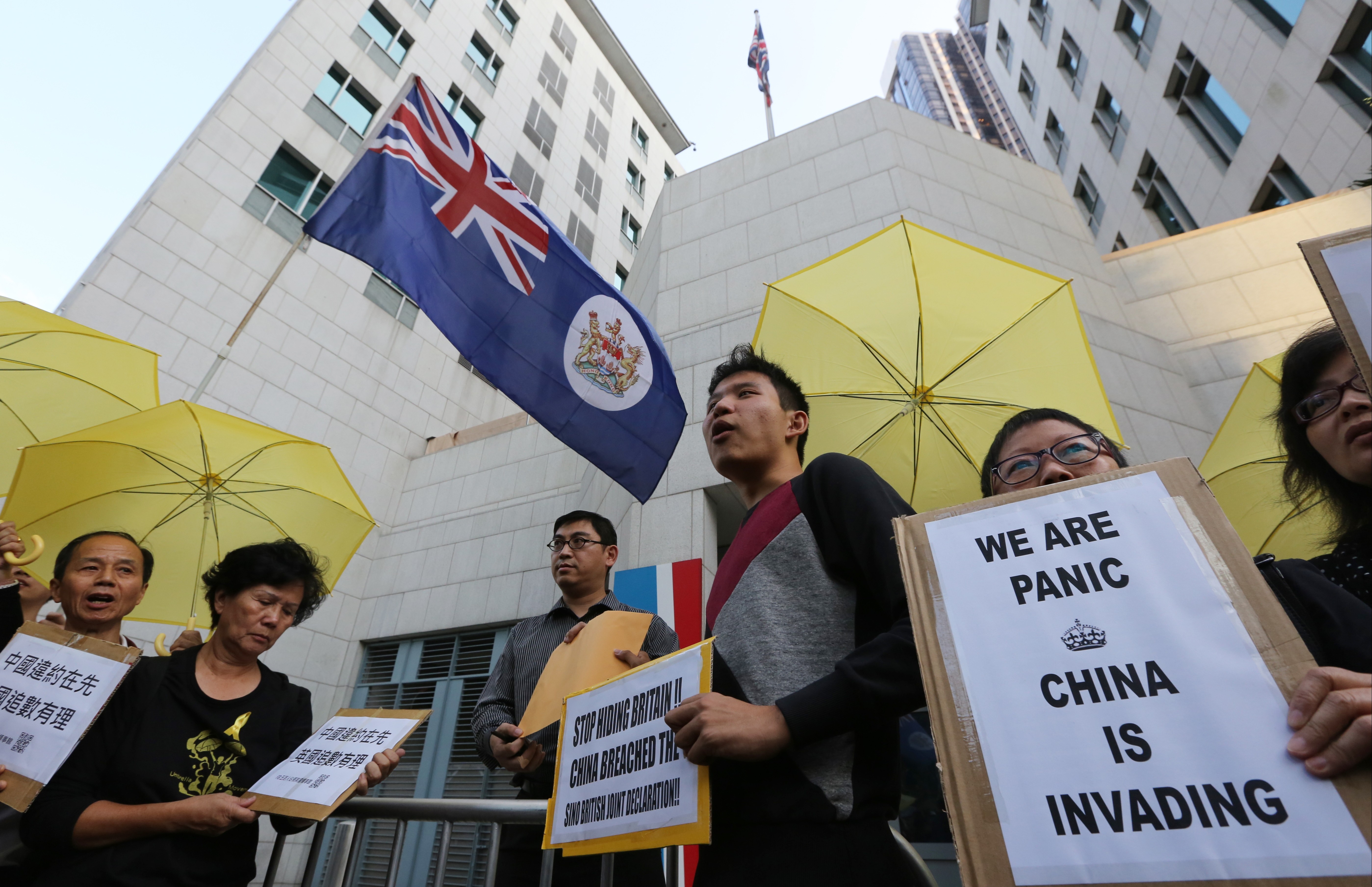 Pro-democracy demonstrators hold the colonial flag and symbolic yellow umbrellas as they stage a protest outside the British consulate in Admiralty, on November 21, 2014, during the Occupy movement in Hong Kong. Photo: Felix Wong