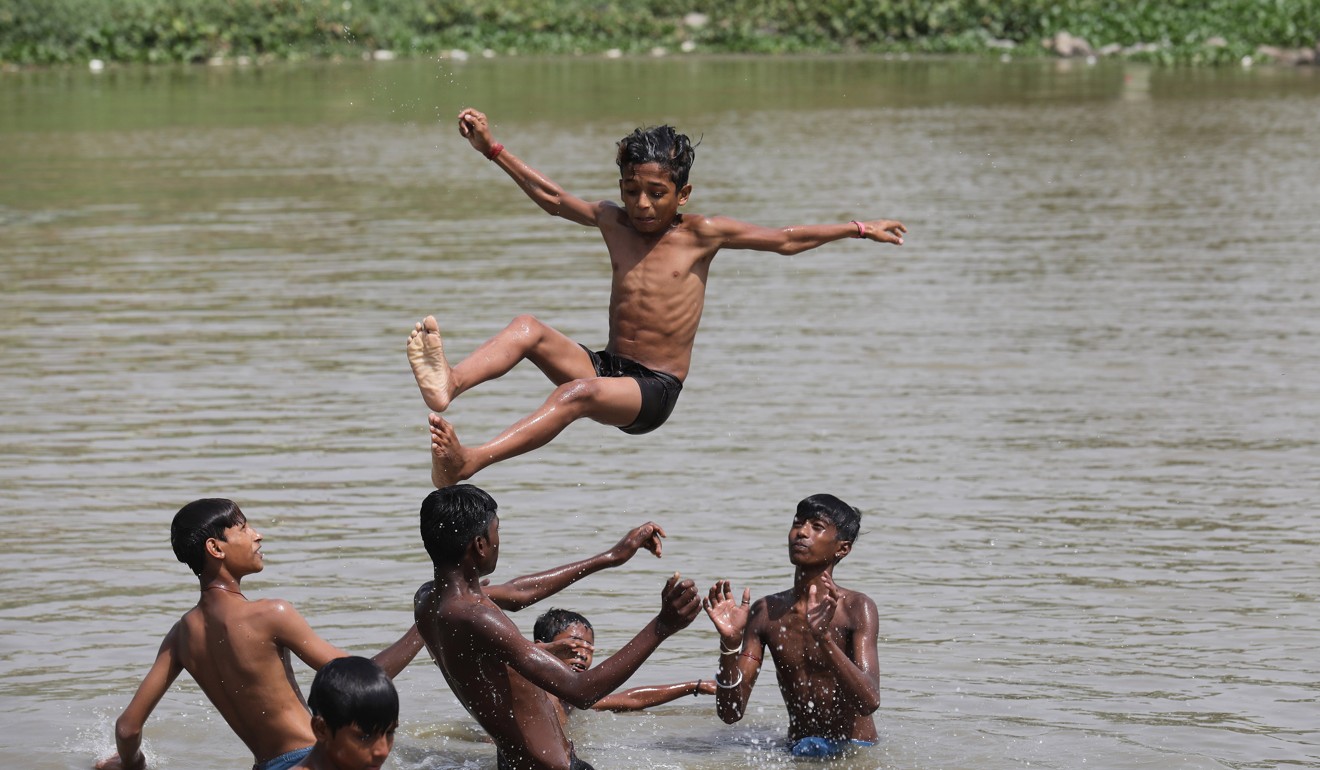 Indian children jump into water on a hot summer day at Yamuna river bed in New Delhi. Lethal heatwaves are going to be common at the rate the world is warming. Photo: EPA