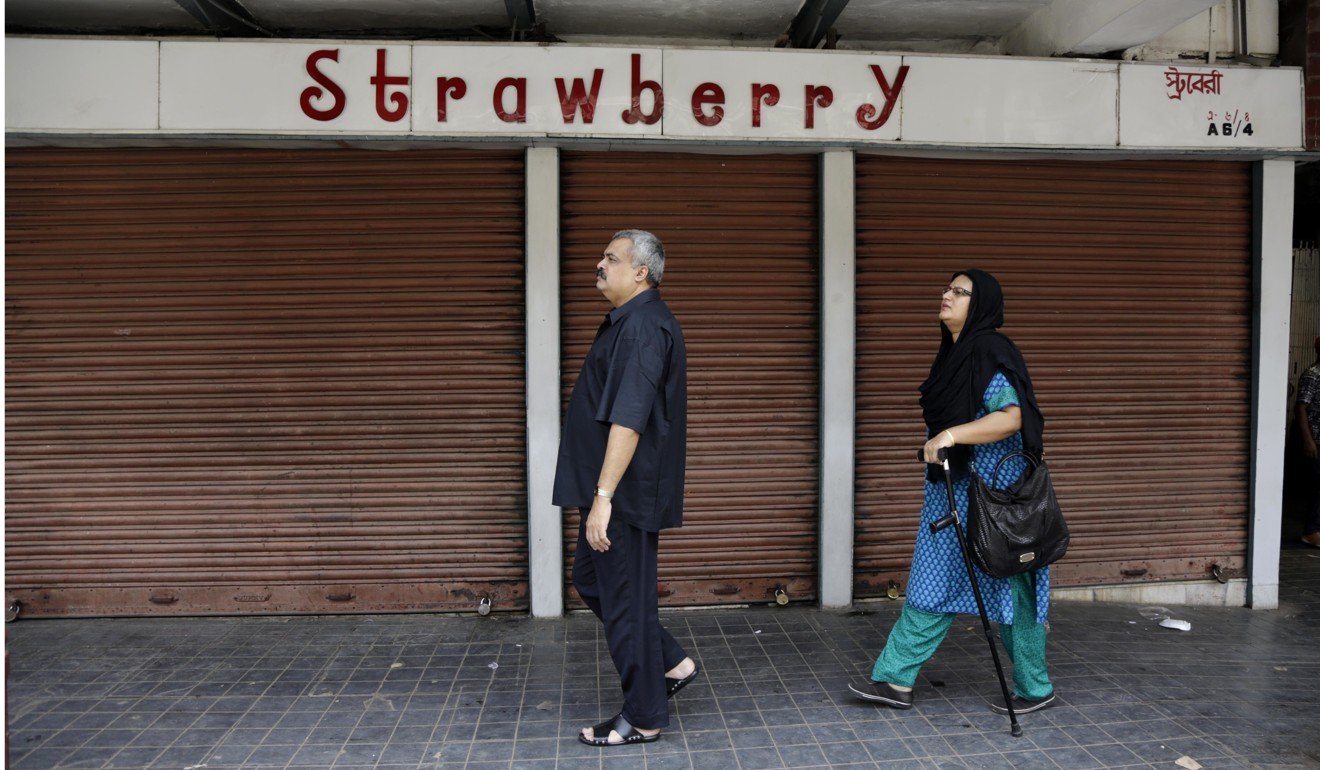 A Bangladeshi tourist couple walk past closed shops during a strike against the nationwide Goods and Services Tax in Kolkata, India. Photo: AP