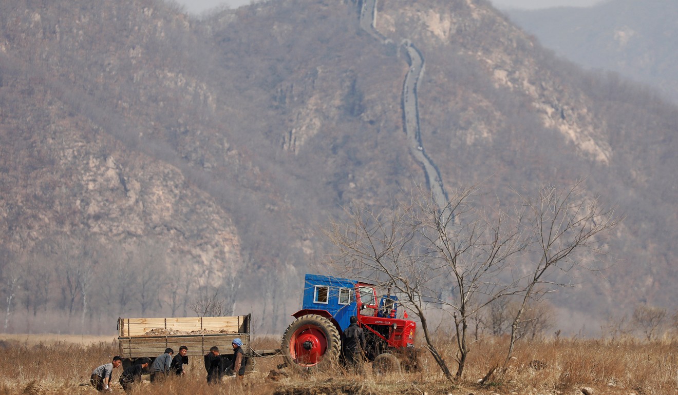 North Korean farmers work in a field as a section of the Great Wall is seen on the Chinese side of the Yalu River, north of the town of Sinuiju in North Korea and Dandong in China’s Liaoning province. Photo: Reuters