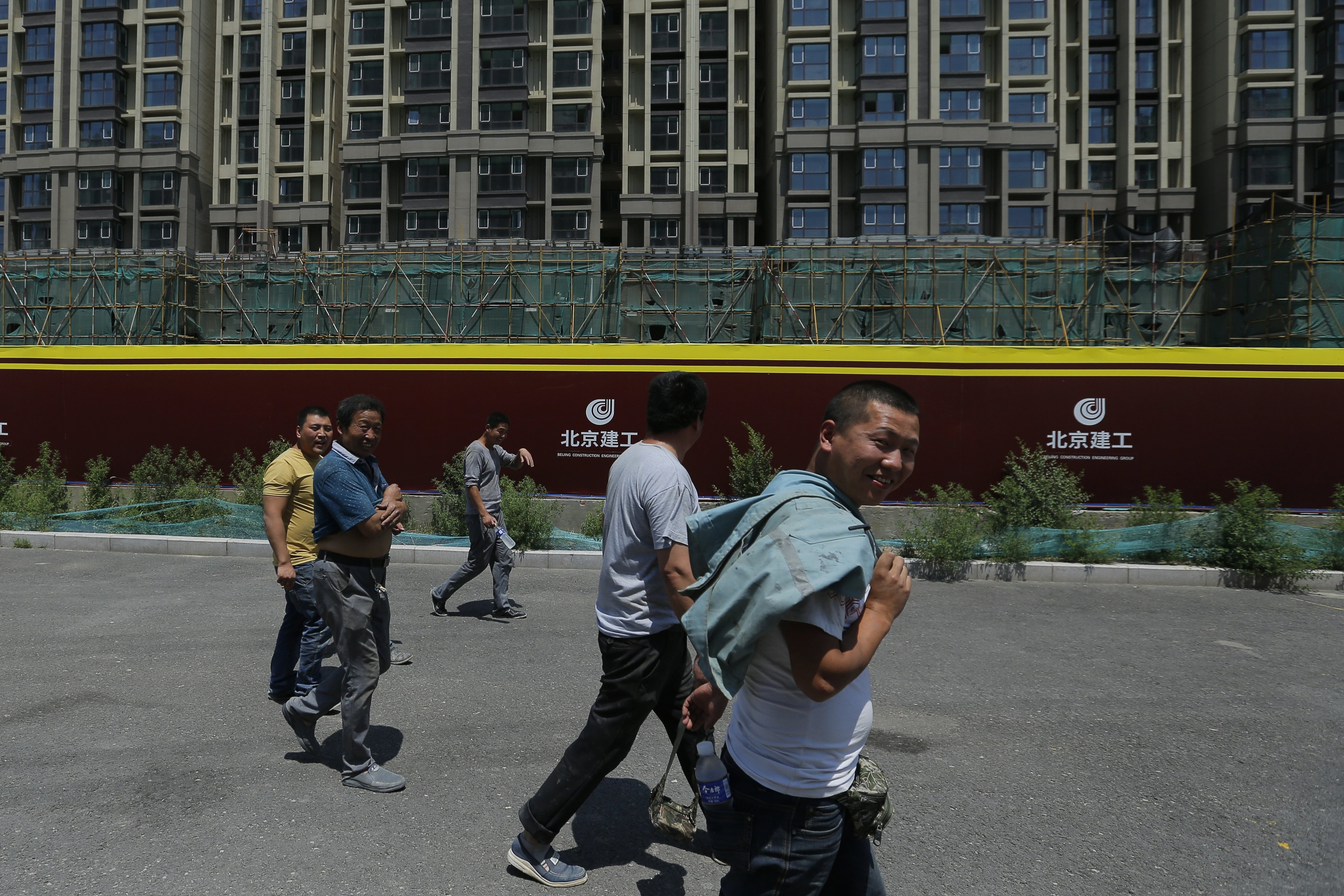 Migrant workers walk past a construction site in Beijing last month. Many Chinese who left their rural hometowns in search of jobs in the country’s booming coastal cities are now in need of new work as construction projects stall and trade volume decreases. Photo: EPA