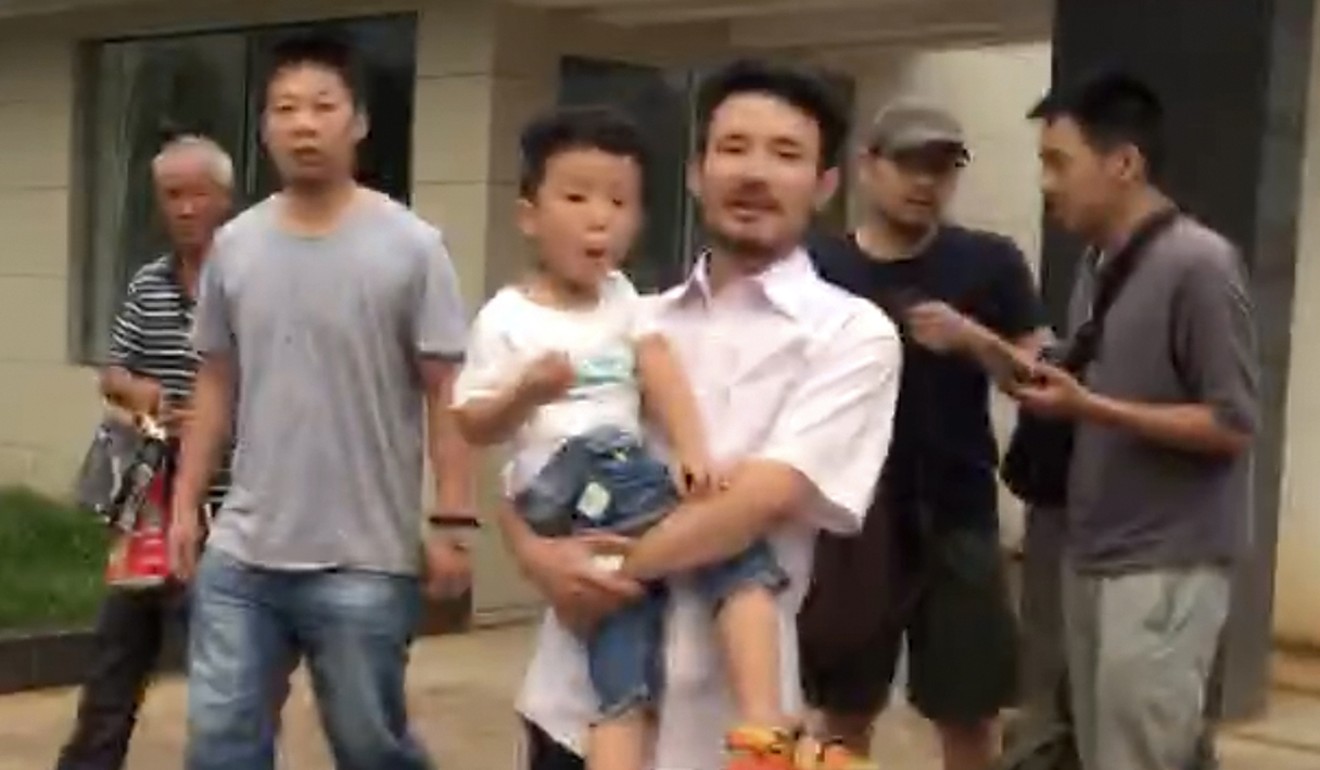 Labor activist Hua Haifeng (centre), carrying his son Bobo, leaves a police station after being released in Jiangxi province on June 28, 2017. Picture: AP
