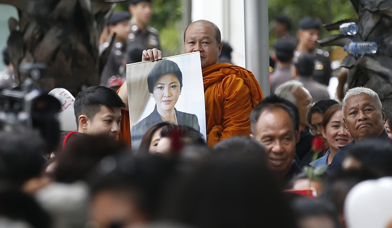 A Thai Buddhist monk holds a picture of former Thai Prime Minister Yingluck Shinawatra as he wait for Yingluck's arrival for her trial. Photo: EPA