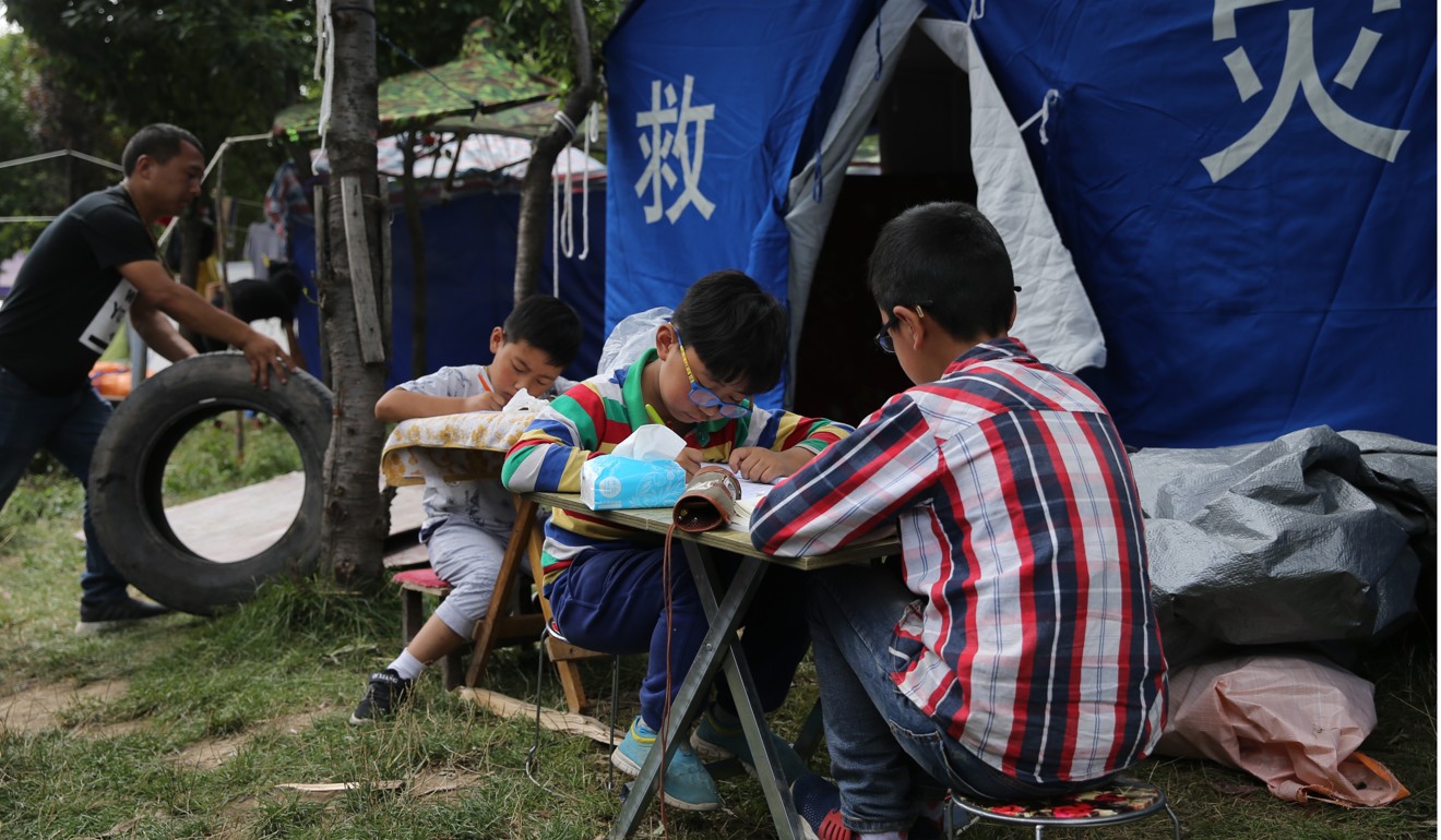 Children do their homework at fold-out tables near their tent. Photo: Sam Tsang