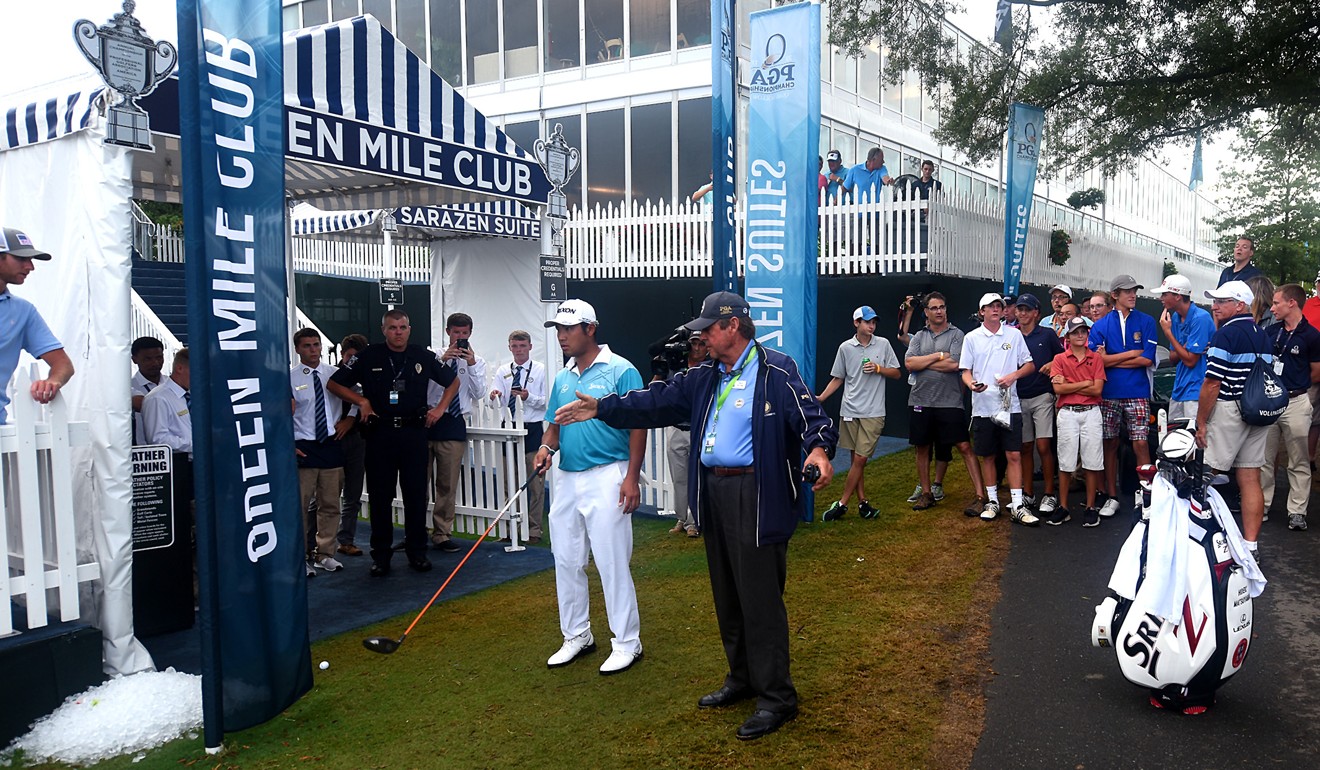 Hideki Matsuyama listens as a rules official after hitting his ball up along a suite area on the 16th fairway. Photo: TNS