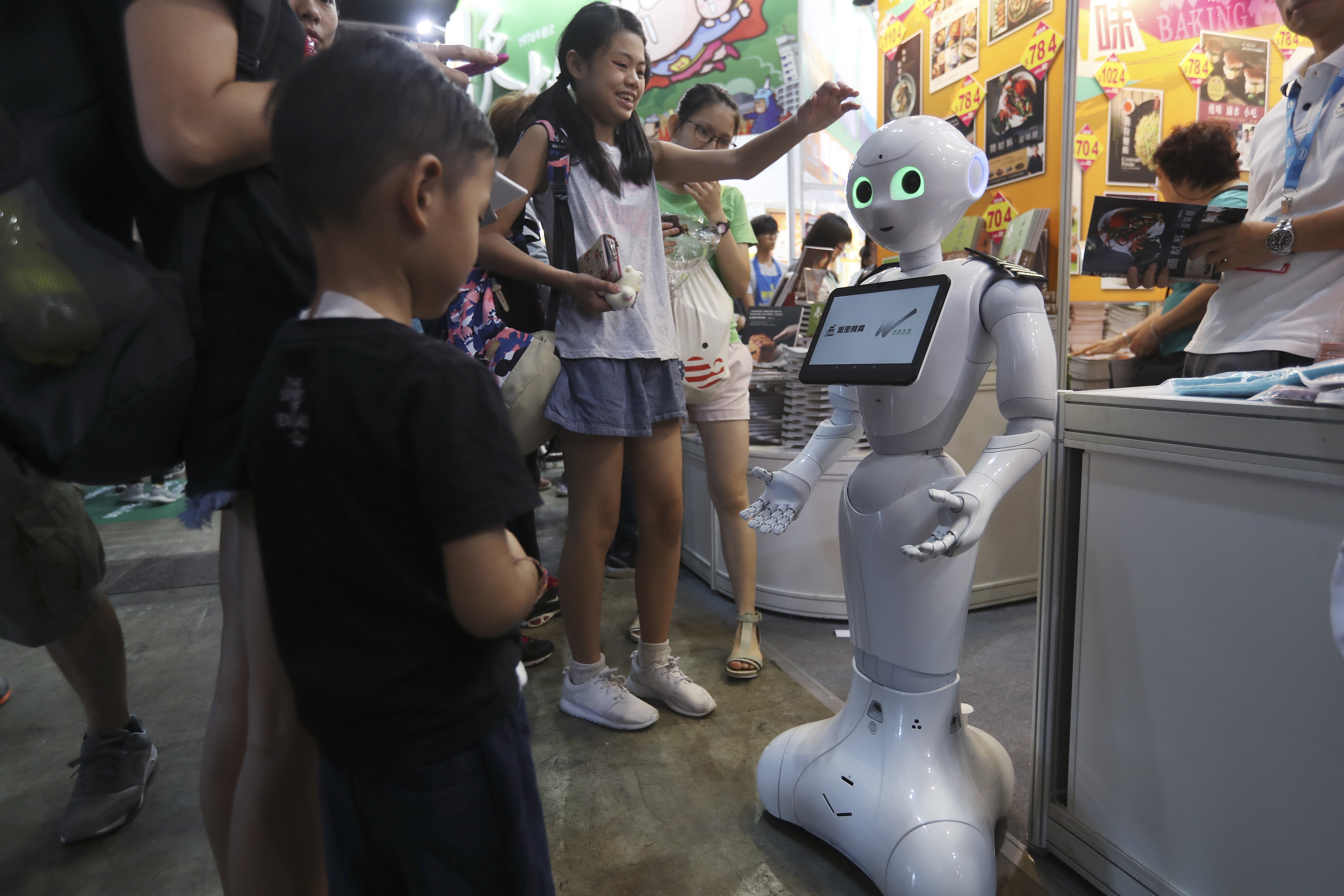 A robot welcomes young visitors to the Hong Kong Book Fair, at the Convention and Exhibition Centre on July 19. Photo: Nora Tam