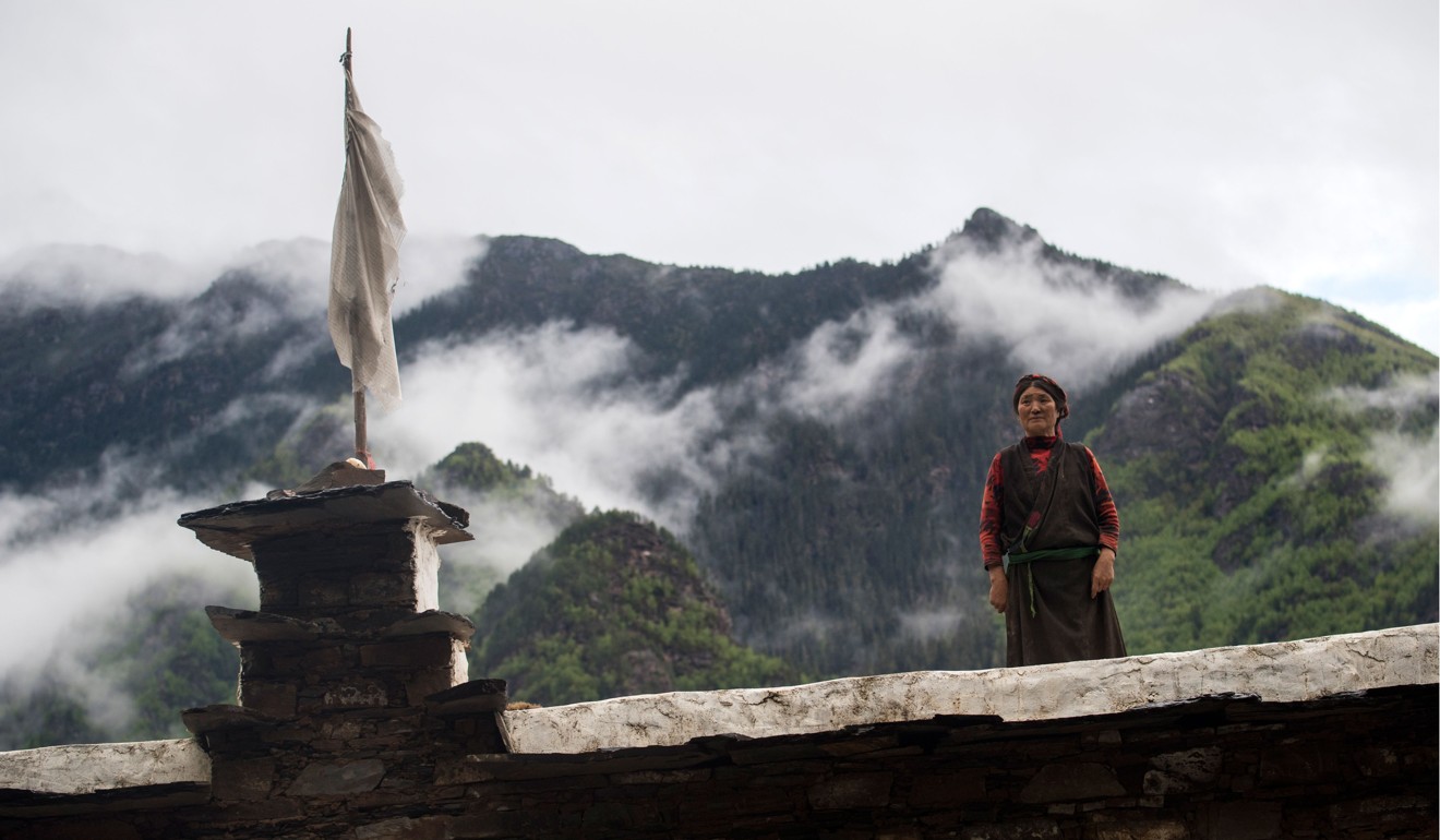 A Zhaba woman stands on the top of a traditional house. Photo: AFP