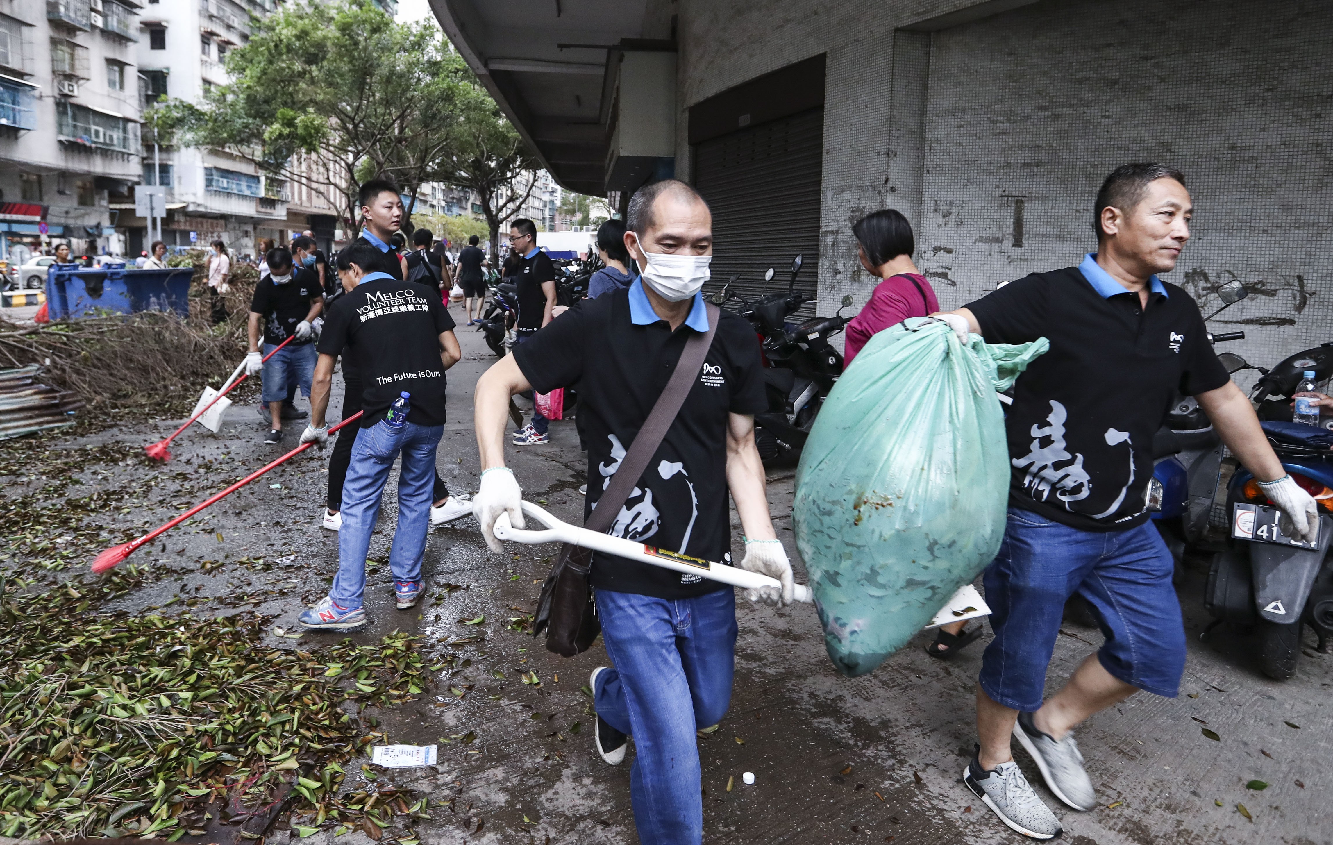 Macau residents clear the streets, covered with piles of rubbish and debris, after the city was hit by two storms in the past week. Photo: Nora Tam