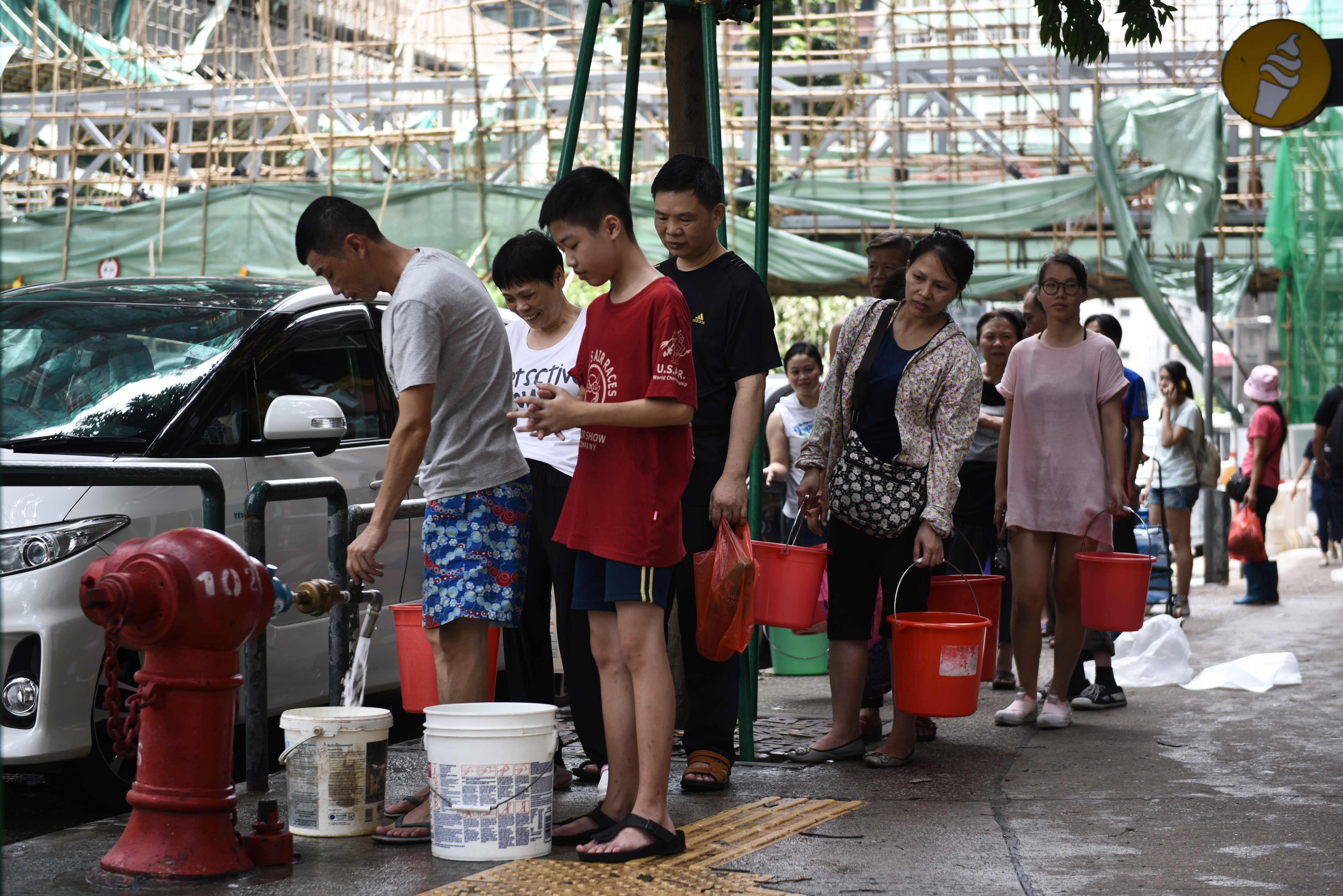 People queue up to collect water from a fire hydrant in Macau on August 24, a day after Typhoon Hato left a trail of destruction, with water supplies badly hit. Photo: AFP