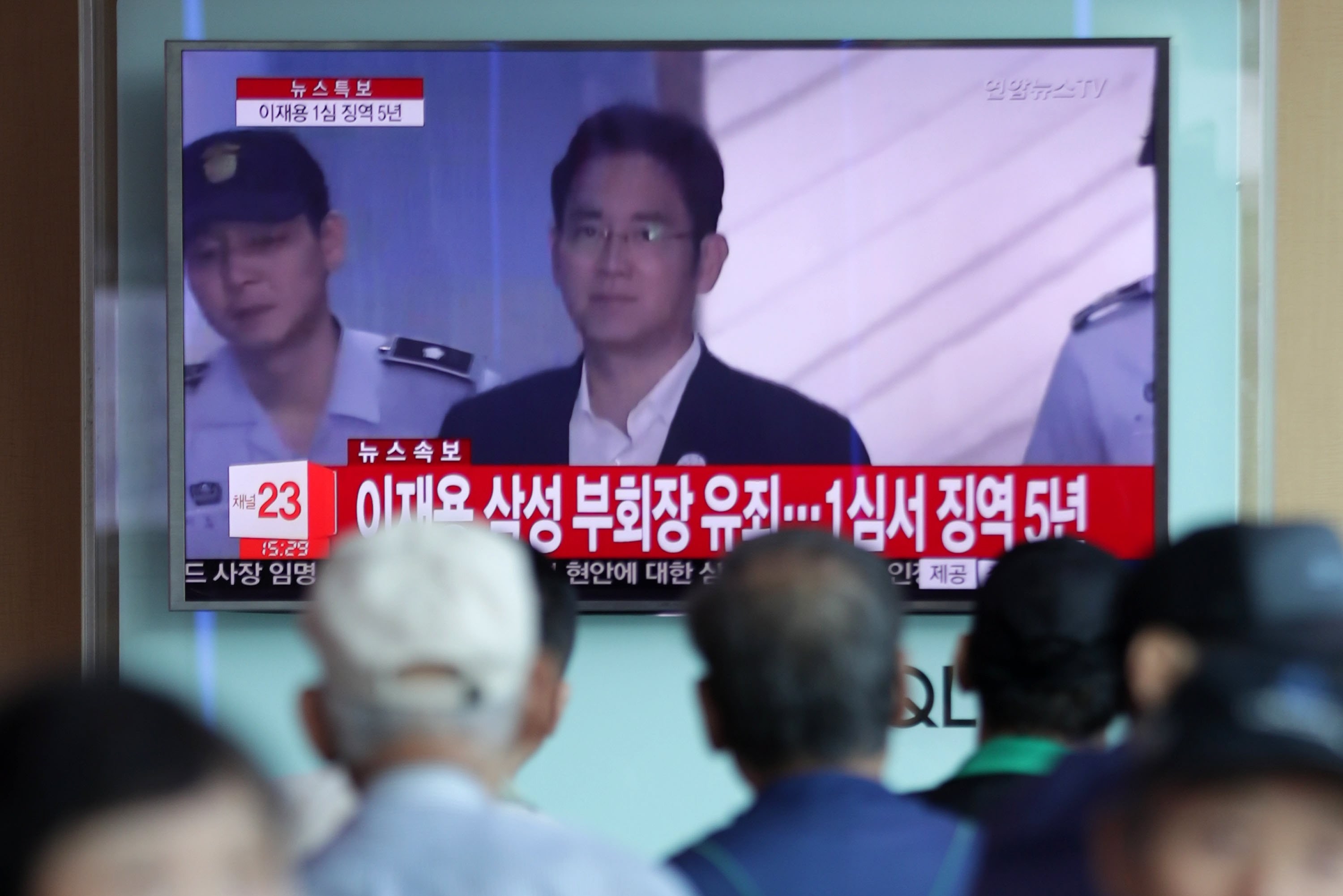 South Korean citizens watch coverage of the sentencing hearing for Samsung Electronics vice-chairman Lee Jae-yong in Seoul on Friday. Lee was jailed for five years after being convicted of bribery and other charges. Photo: Yonhap