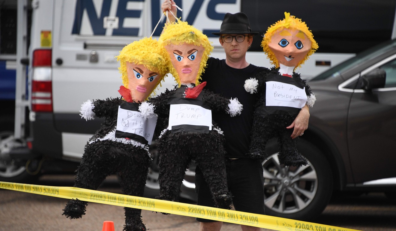 A demonstrator holds up what are supposed to be Donald Trump dolls as he protests the president’s visit to Texas. Photo: AFP