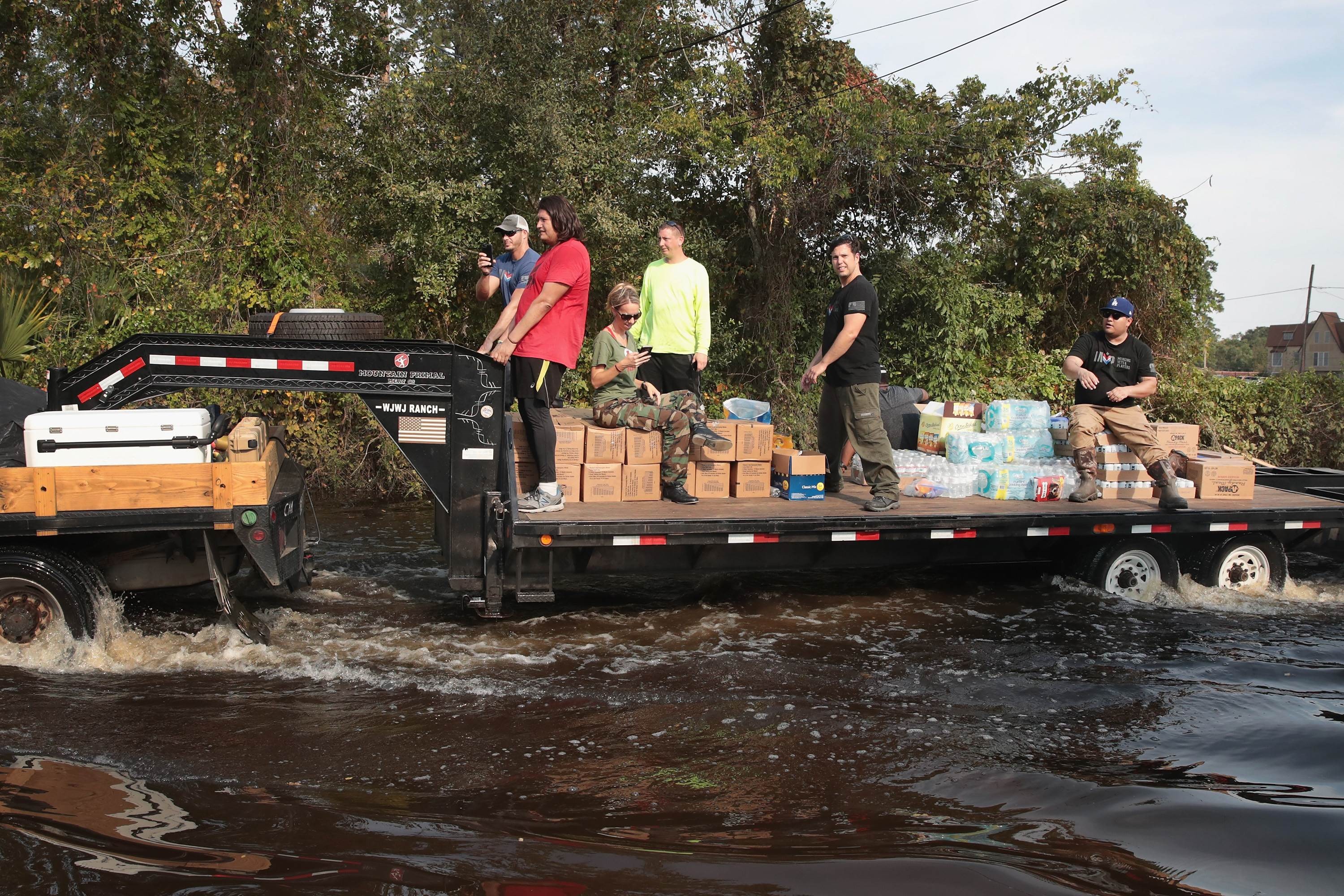 Volunteers distribute food, water and pet food to flood victims from the back of a lorry trailer. Photo: AFP