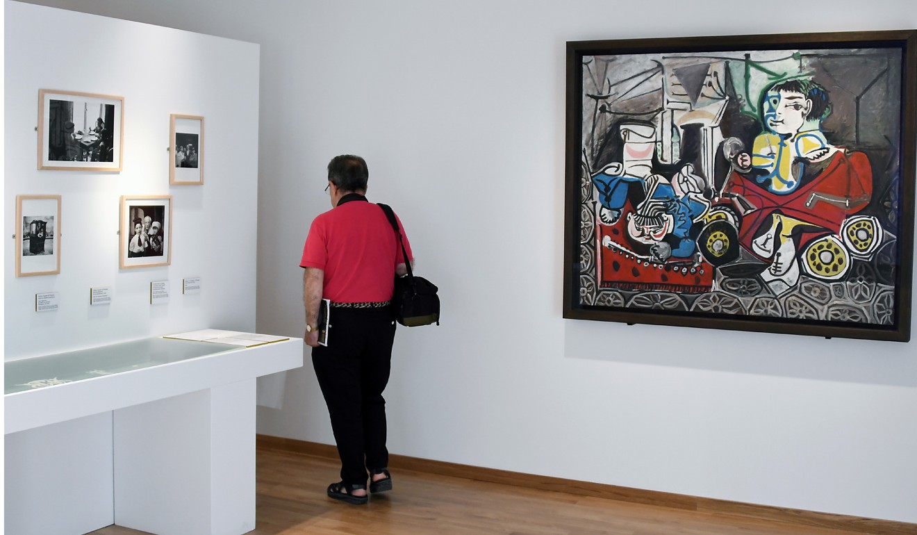 A man looks at pictures next to ‘Claude et Paloma’ by Pablo Picasso. Photo: AFP