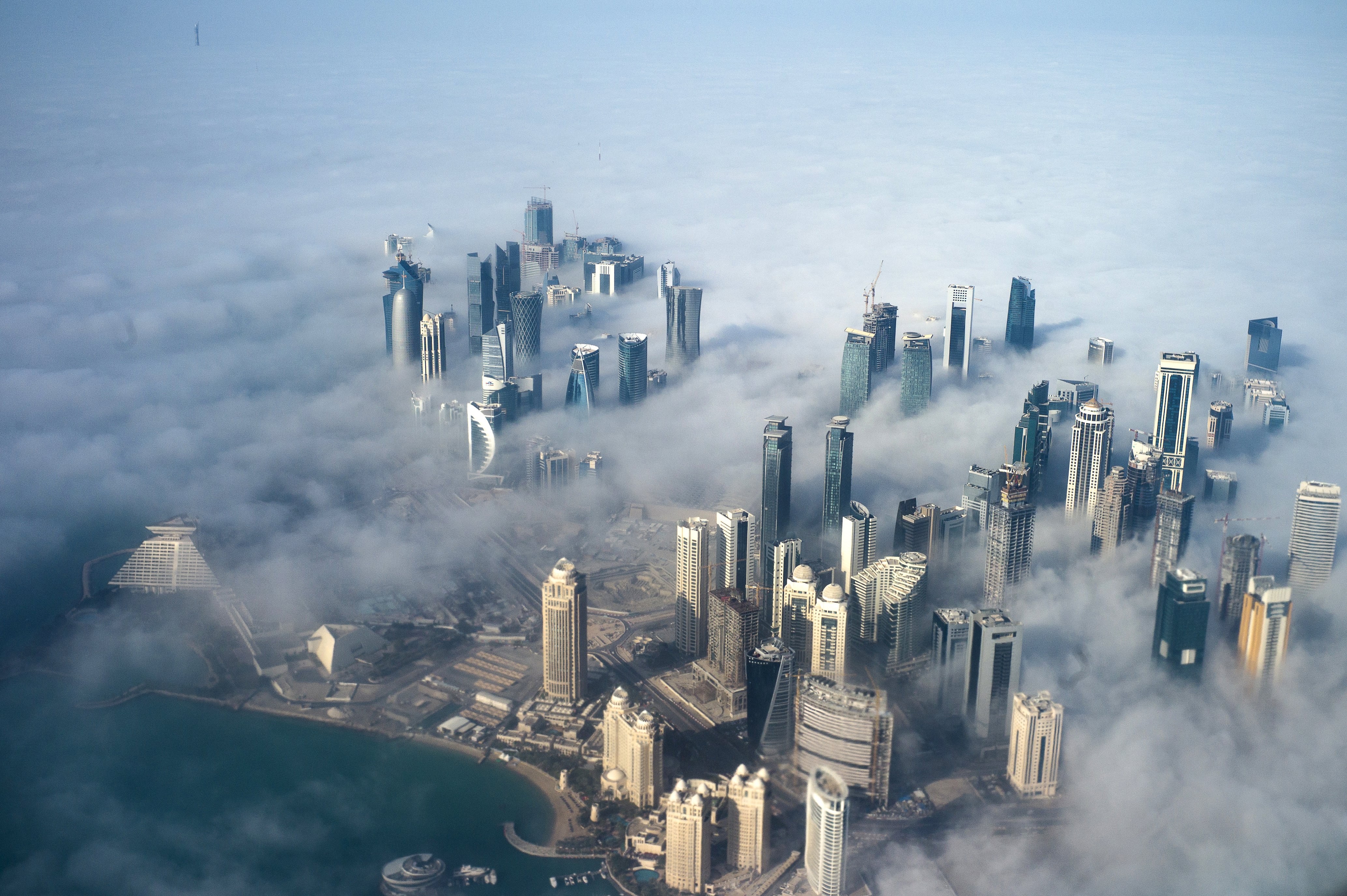 High-rise buildings emerge through fog covering the skyline of Doha, a city where traffic, a lack of pavements for walking and cycle lanes add to daily stresses. Photo: EPA