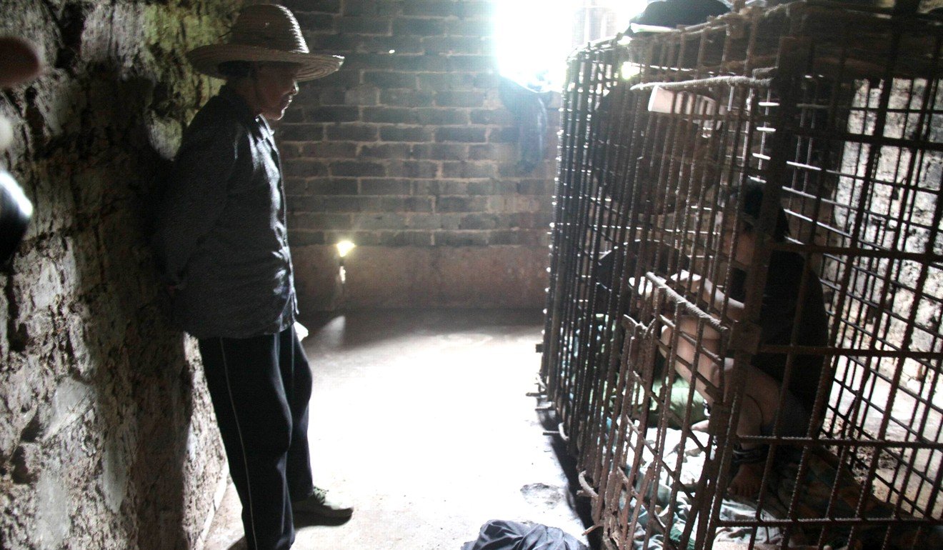 Wu Yuanhong, 42, a mentally ill man, eats his lunch in a cage in Jiangxi, China. Photo: AFP