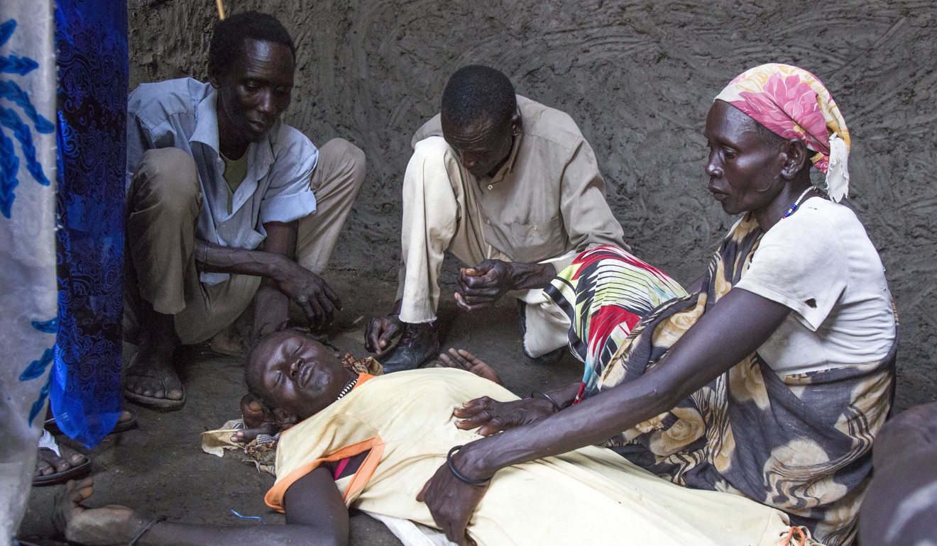 Family members gather around a 26-yer-old malaria sufferer in South Sudan. Photo: AFP