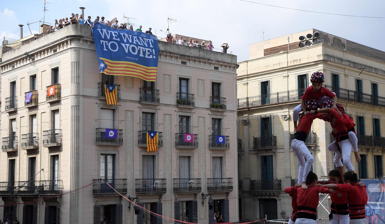 Members of the Castellers de Barcelona human tower perform in front of a building with a banner in favour of the referendum in Sant Jaume square, Barcelona. Photo: AFP