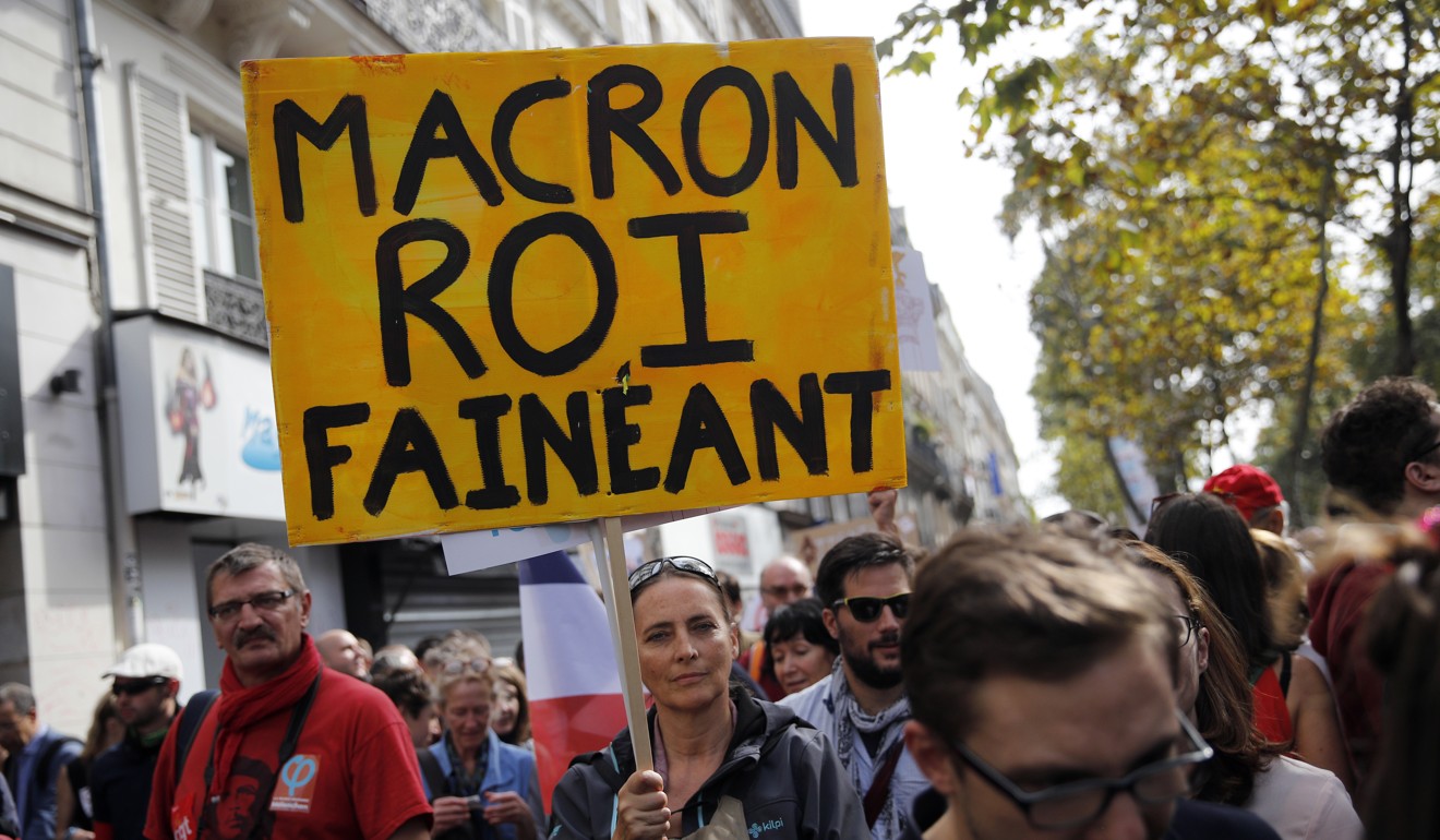 A demonstrator holds a placard reading “Macron King slacker” during a protest over the president's labour reform in Paris on Saturday. Photo: AP