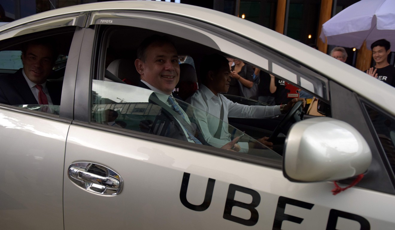 US Ambassador Willam Heidt, front seat, and Uber's Asia Pacific chief business officer Brooks Entwistle, back seat, sit in a Uber car travelling along a street in Phnom Penh. US-based Uber, the world’s biggest ride-hailing service, makes its debut in the capital Phnom Penh on September 28. Photo: AFP
