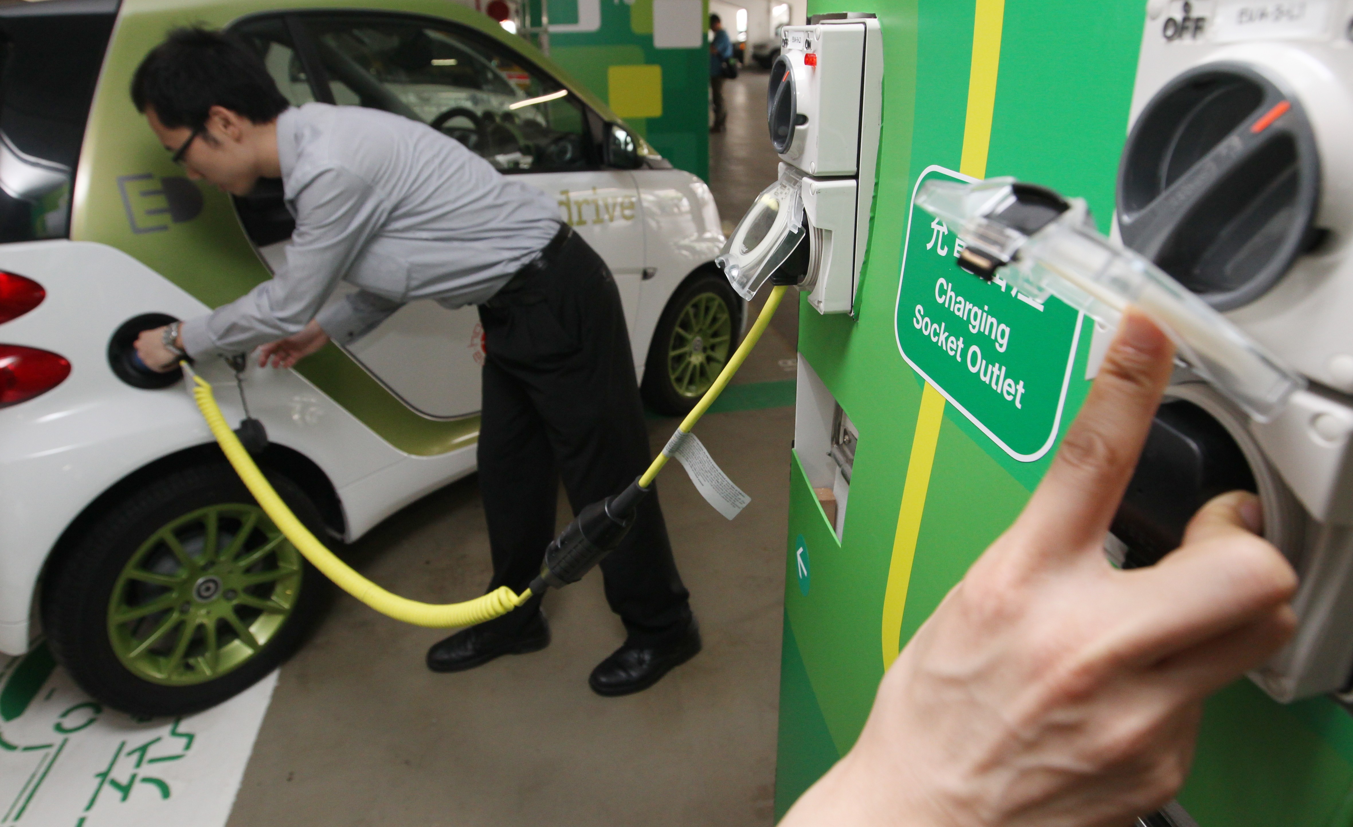 Officials show how to charge electric vehicles at the opening ceremony of the government's publicity campaign on electric vehicles and charging points in Central, in May 2012. Photo: Felix Wong
