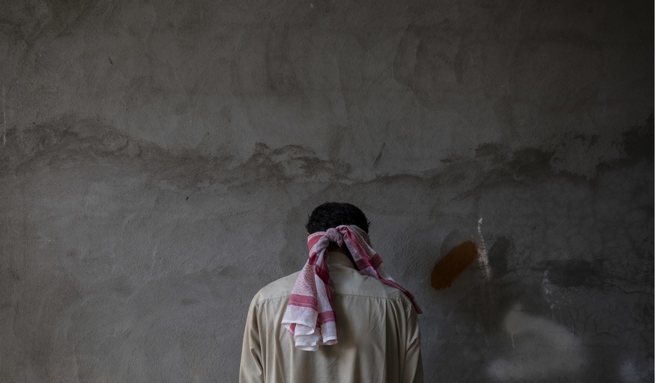 A blindfolded Islamic State suspect stands against a wall facing away from security officers at a Kurdish screening centre outside Kirkuk on Tuesday. Photo: AP