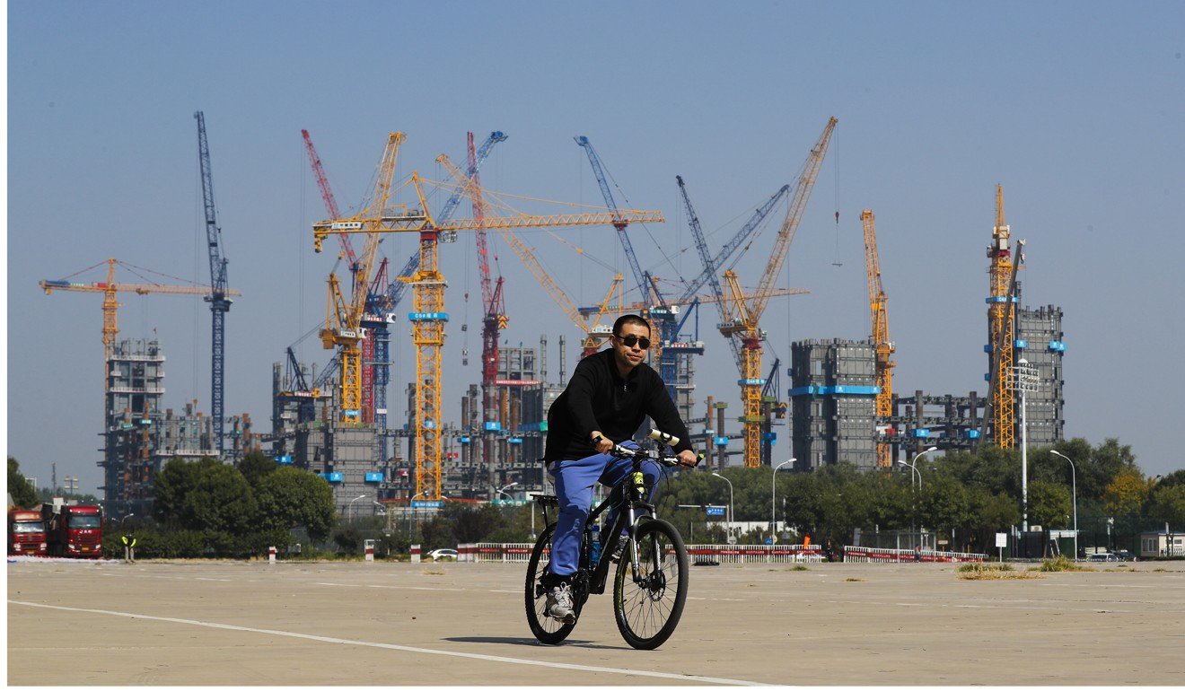 A man cycles past a construction site near the Olympic Park in Beijing this month. Photo: AP