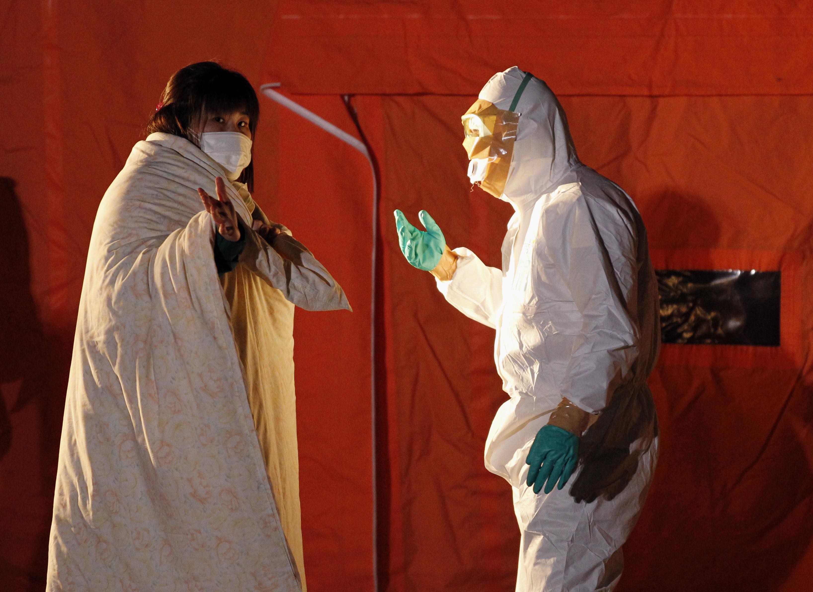 An official in protective gear talks to a woman from the evacuation area near the Fukushima nuclear plant in Koriyama in March 2011. Photo: Reuters