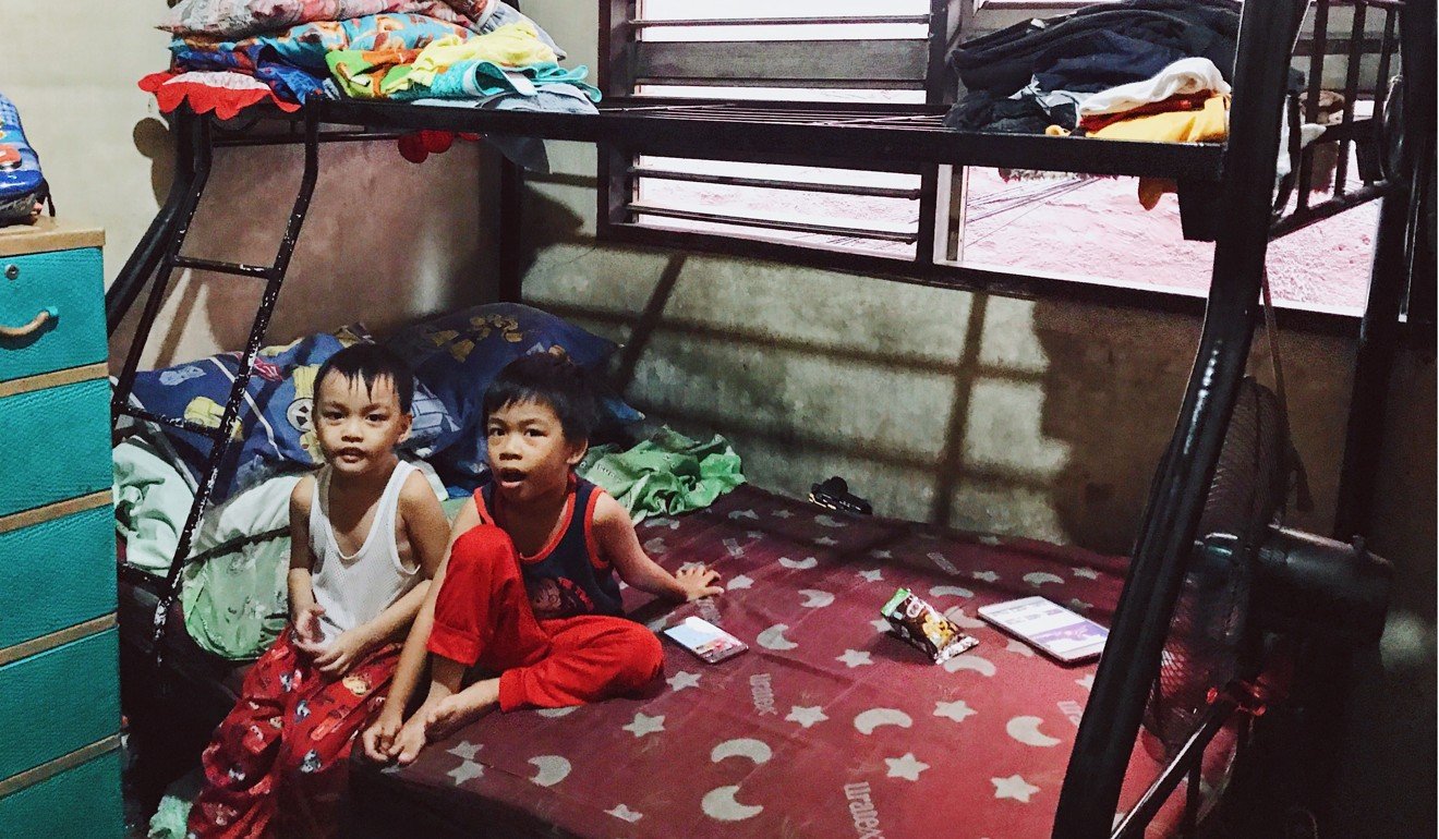 Two of Manuel S. Adad’s three sons sit in their family home, which is made up of just two bedrooms, with four bunk beds and some mattresses on the floor. Photo: Karim Raslan Two of Manuel S. Adad’s three sons sit in their family home, which is made up of just two bedrooms, with four bunk beds and some mattresses on the floor.
