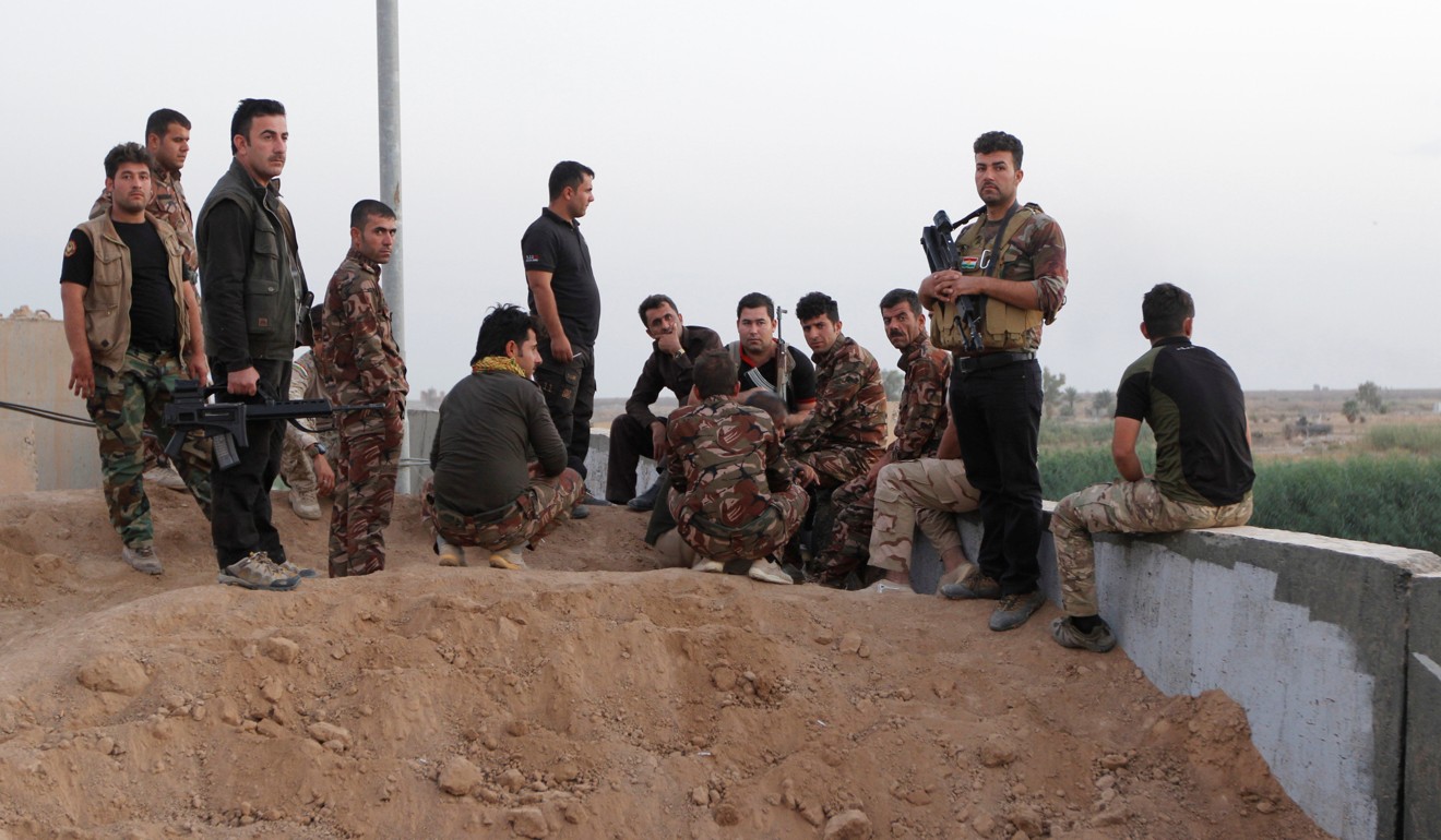 Kurdish Peshmerga fighters lounge against a wall in Kirkuk, Iraq. Photo: Reuters