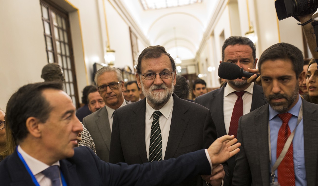 Spain's Prime Minister Mariano Rajoy, centre, is questioned by journalists as he leaves the Spanish parliament in Madrid, on Wednesday, October 18, 2017. Rajoy on Wednesday urged Catalonia's leaders to back down from their bid to gain independence for the region, a day ahead of a central government deadline that could significantly deepen the country's political crisis. Photo: AP