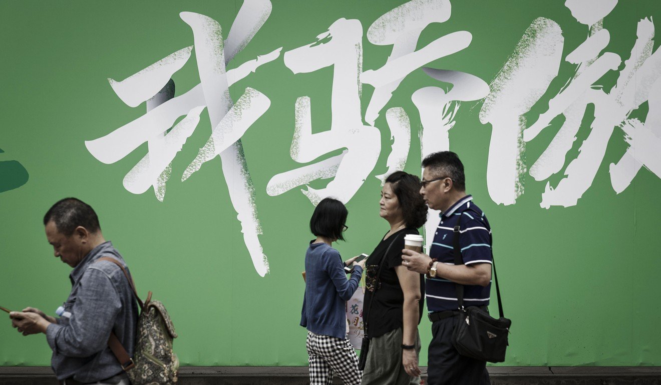 Pedestrians and shoppers walk past an advertisement featuring the words “My Pride” at a shopping area in Shanghai. In 1978, there were over 250 million people living in poverty in China. By 2010, the number had fallen to 29 million. Photo: Bloomberg