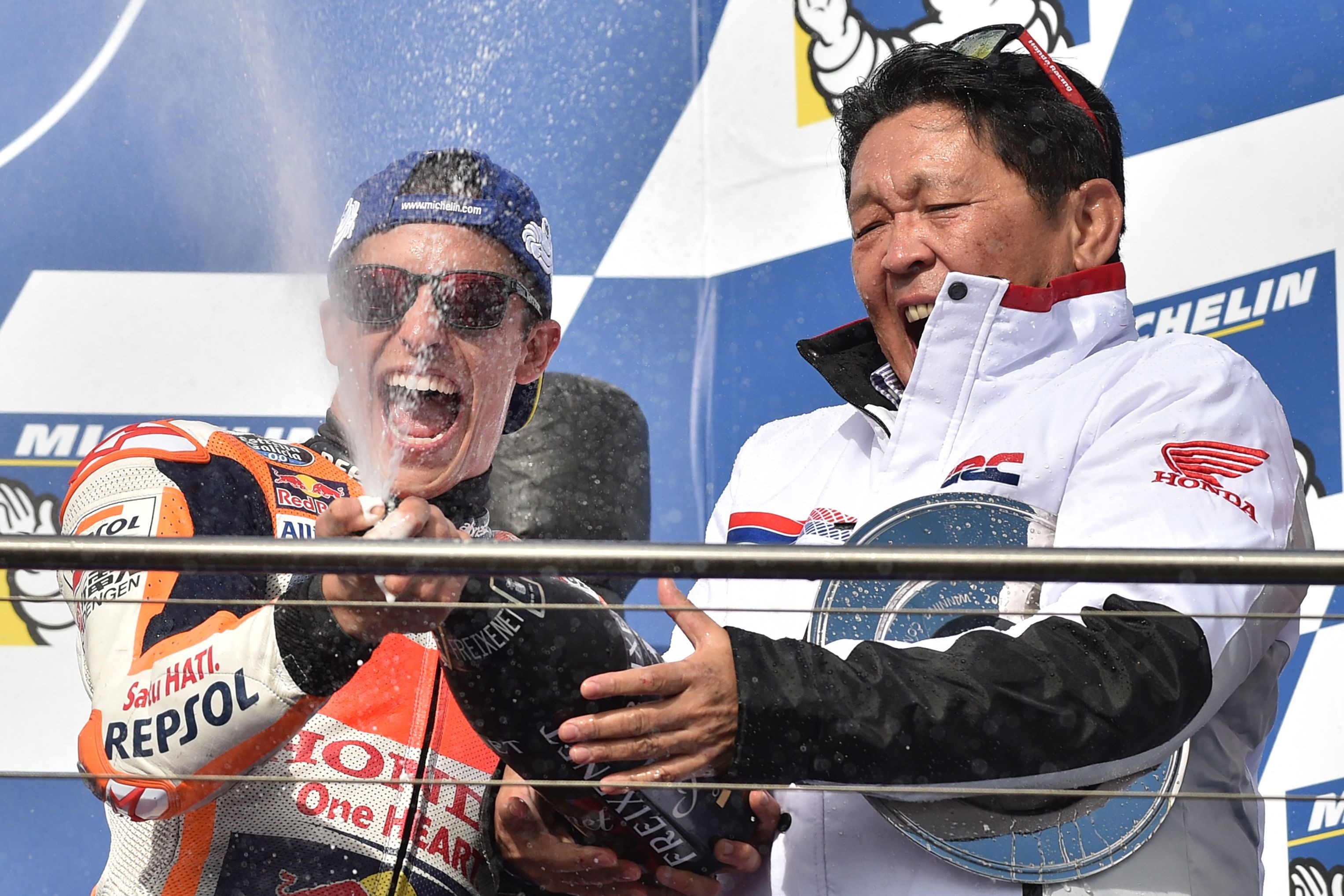 Honda rider Marc Marquez (L) celebrates his victory with Honda team boss Shuhei Nakamoto on the podium after the Australian MotoGP Grand Prix. Photo: AFP