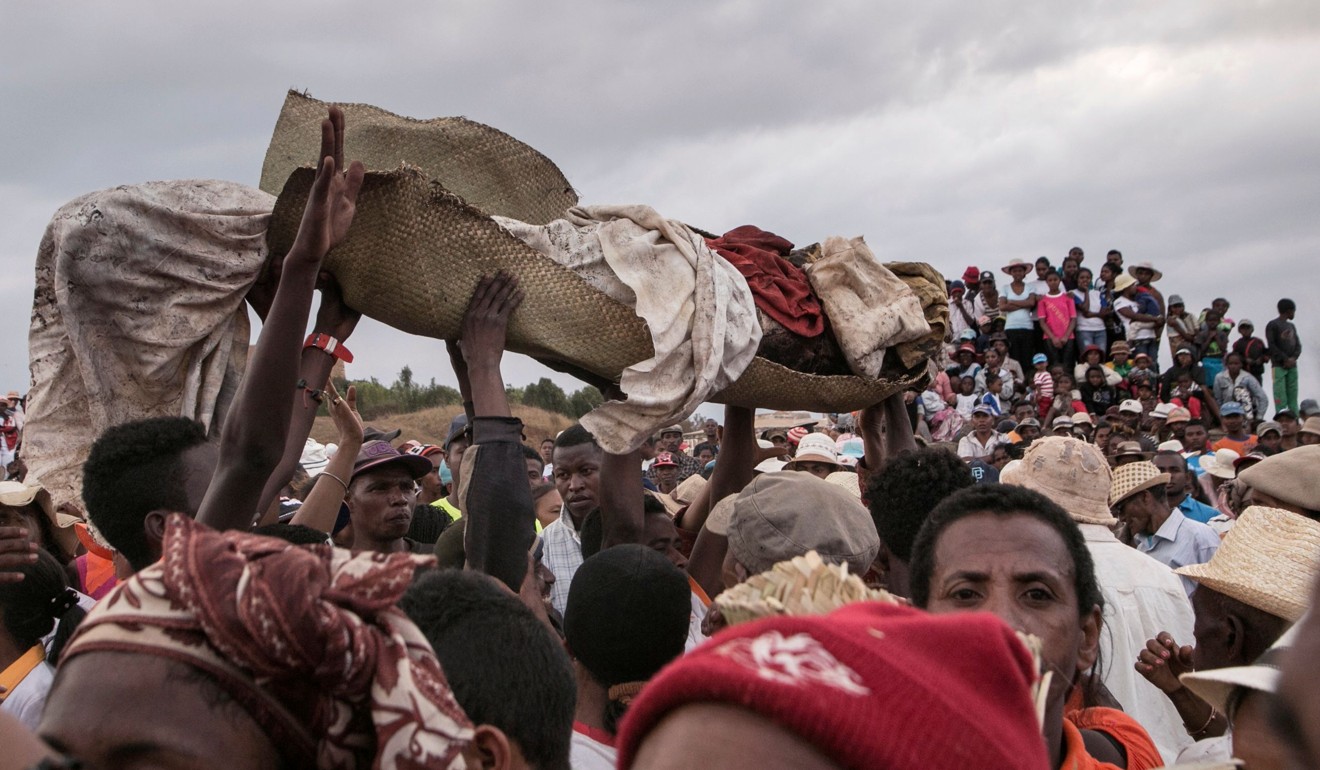 People carry a body wrapped in a sheet after taking it out from a crypt. Photo: AFP