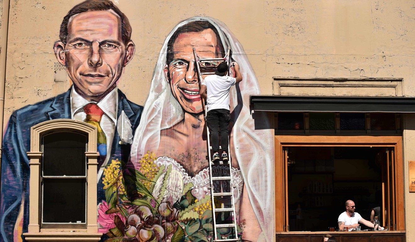 Australian street artist Scottie Marsh painting a mural of former Australian prime minister Tony Abbott as the bride of Tony Abbott, in Sydney. Photo: AFP