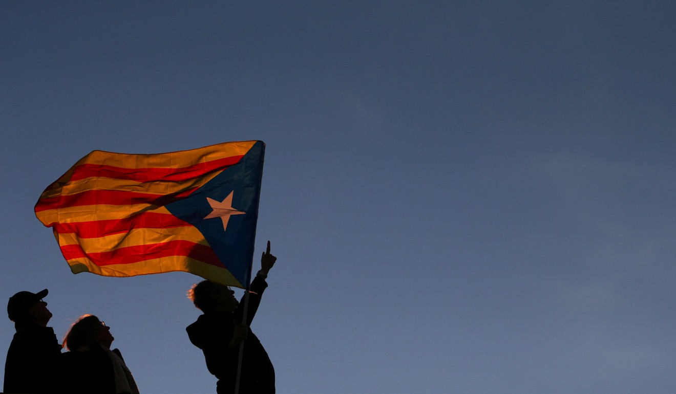 A man gestures to a police helicopter as he waves an “Estelada” flag on top of a building during a demonstration called by pro-independence associations asking for the release of jailed Catalan activists and leaders in Barcelona. Photo: Reuters