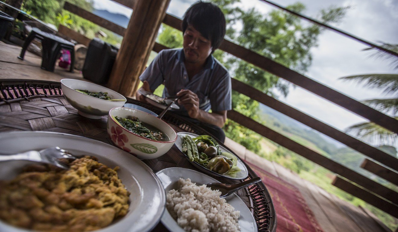 Local villagers dine with a traveller at their home in Pha Mon village. Photo: G Adventures