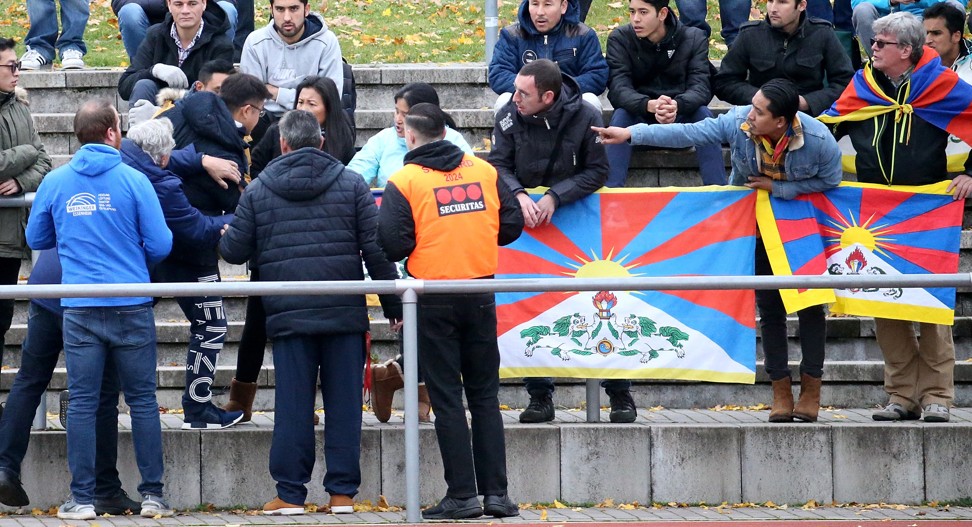 A Chinese spectator attempts to tear away a Tibetan flag raised by a group of spectators in protest of China’s politics regarding Tibet. Photo: AP