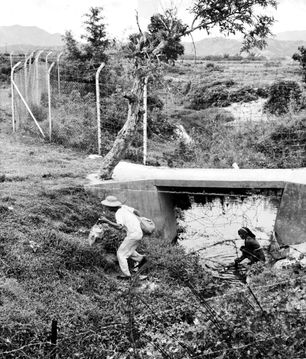 An illegal immigrant enters Hong Kong the hard way, through barbed wire underneath a bridge, in May 1962.