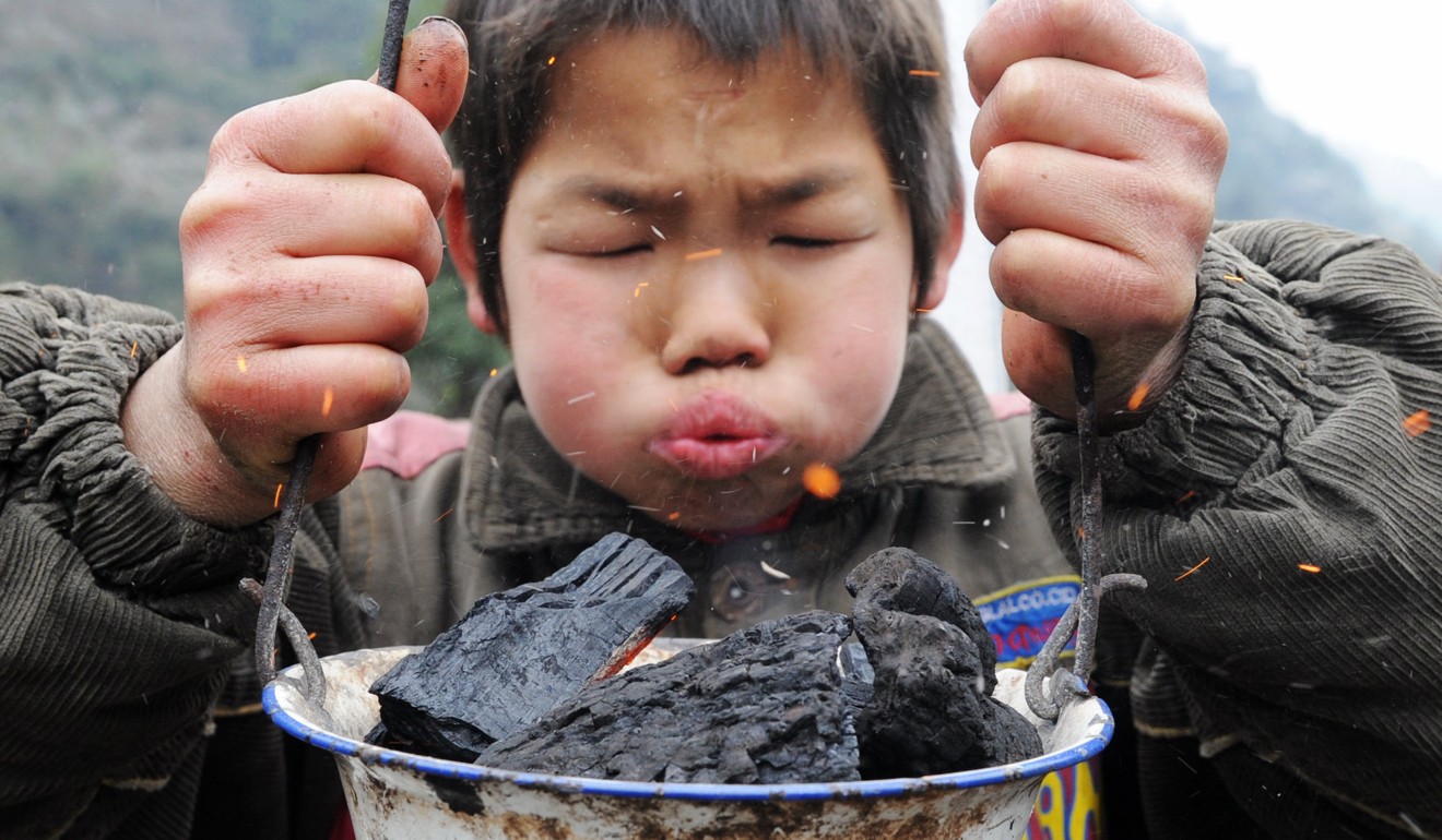 A boy in Hunan province tries to keep warm in front of a portable stove. Photo: Xinhua