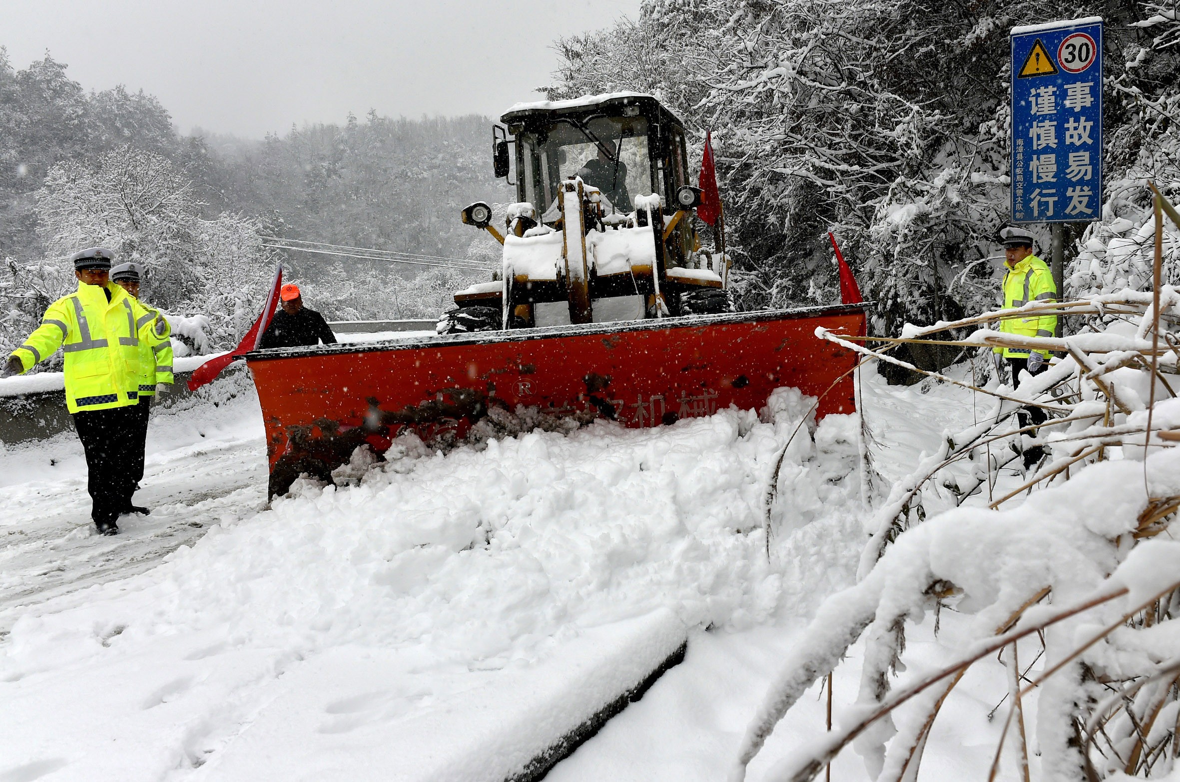 A snow grader clears a path on a dangerous road in Nanzhang county, Hubei province. Photo: Xinhua