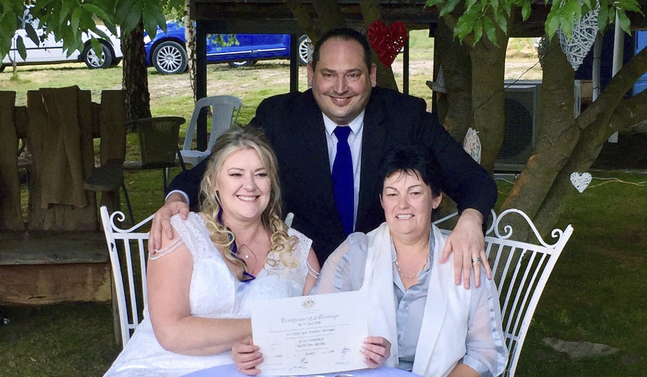 Lainey Carmichael and Roz Kitschke, with celebrant Jason Betts, pose with the couple’s marriage certificate after they tied the knot in Tasmania. Photo: AP