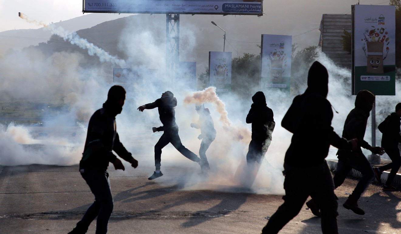 A Palestinian protester hurls a smoke-grenade towards Israeli security forces during clashes near the Hawara checkpoint, south of the West Bank city of Nablus, on January 12, 2018. Photo: AFP