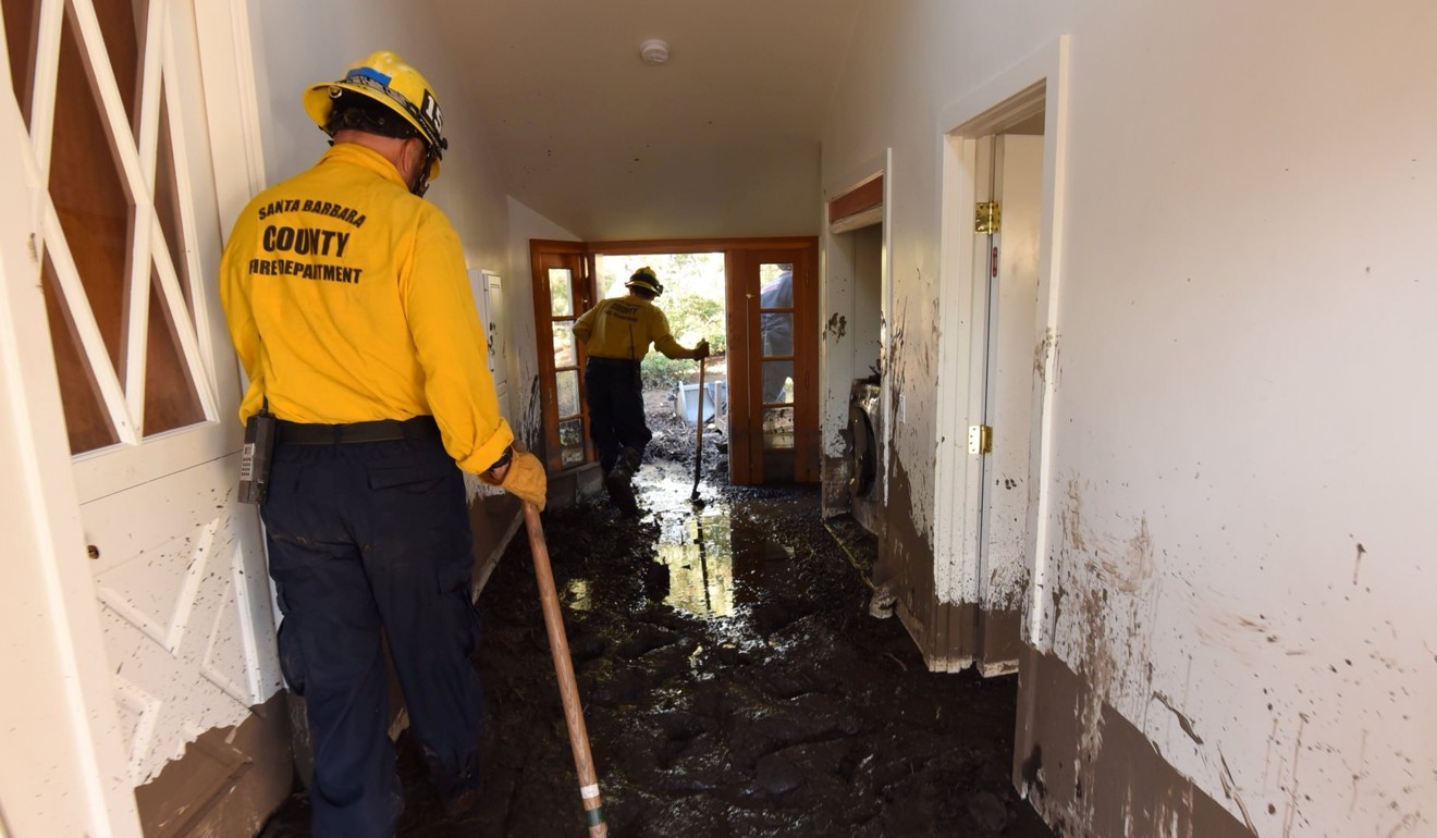Santa Barbara County firefighters Rick Pinal and Vince Agapito climb through a home destroyed by mud and debris in Montecito, California, on January 13, 2018. Photo: Santa Barbara County Fire/Handout via Reuters