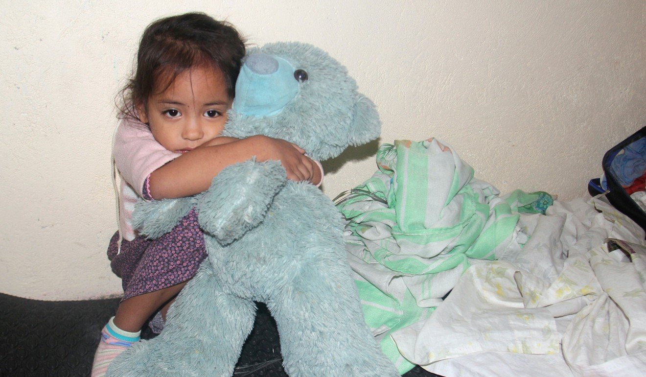 A girl hugs her teddy bear as her family takes shelter in a school. Photo: Reuters