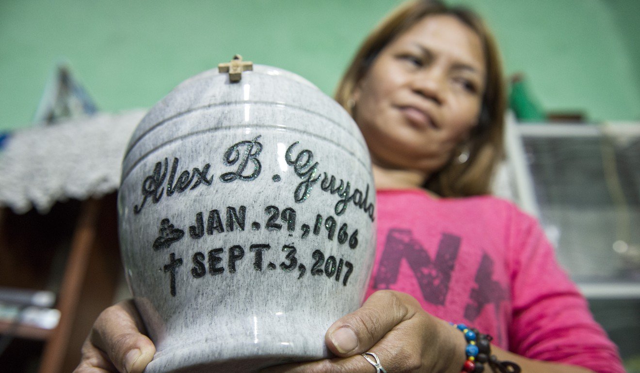 Rose Guyala holds the urn of her husband, Alex, who was shot by a masked man on a motorcycle as the couple arrived home on their tricycle. “I even felt the heat of the bullet,” Rose says. 