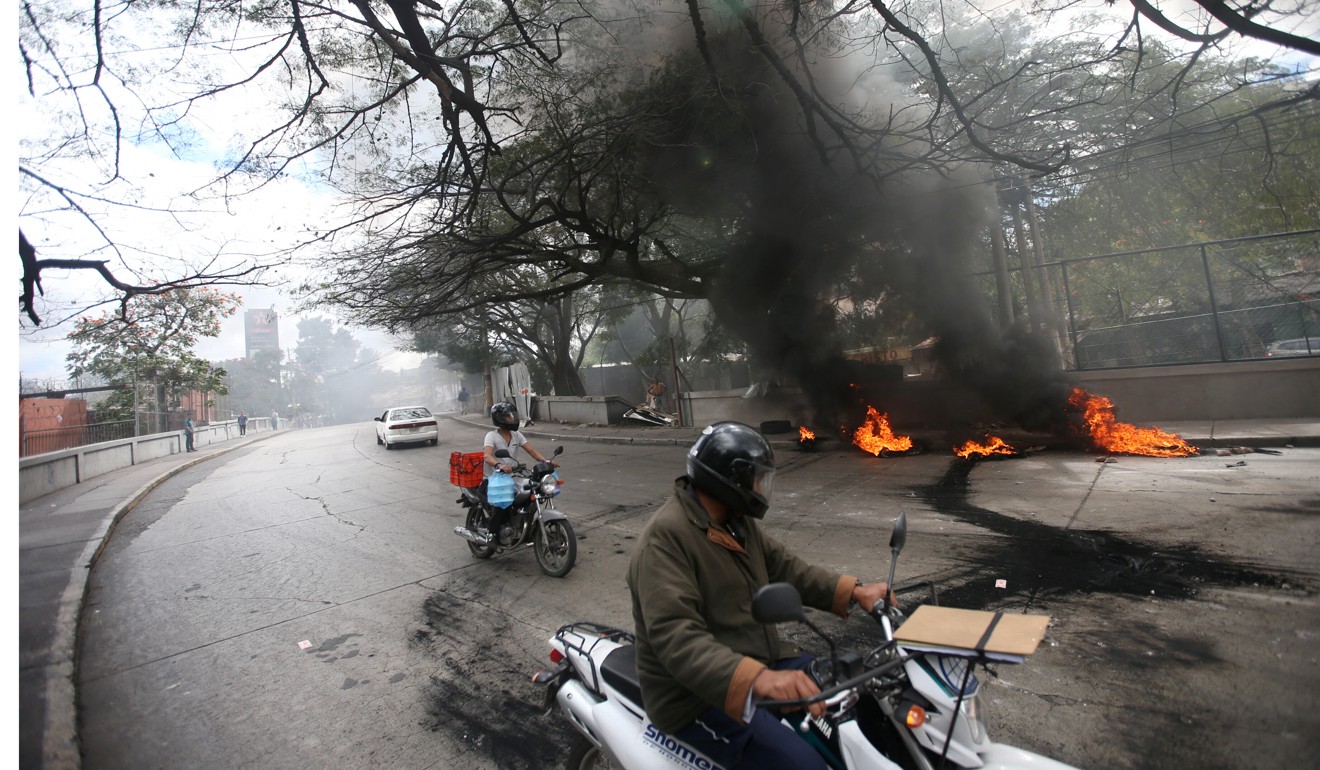 People pass burning tyres during a protest in Tegucigalpa. Photo: Reuters