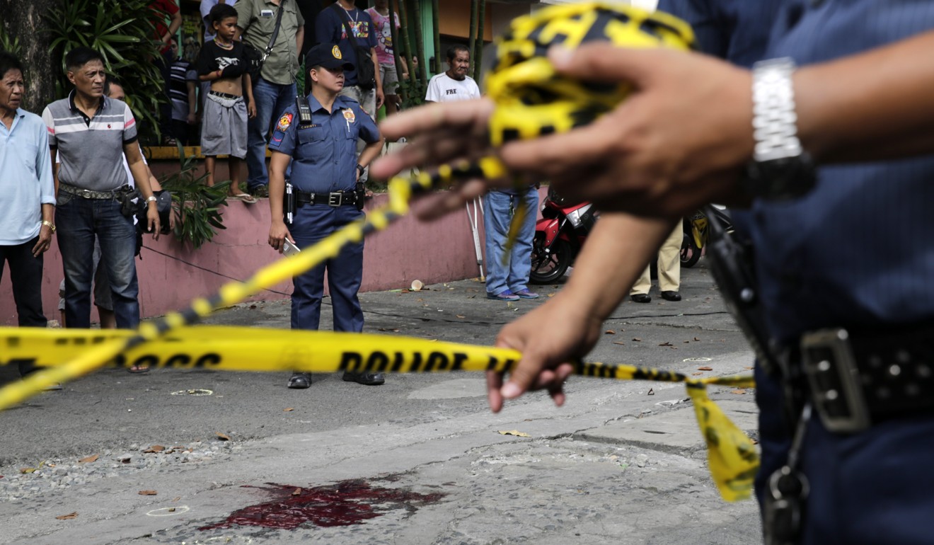 Filipino policemen install police line around the scene where a man was shot in an alleged extra judicial killing in Manila earlier this month. Photo: EPA